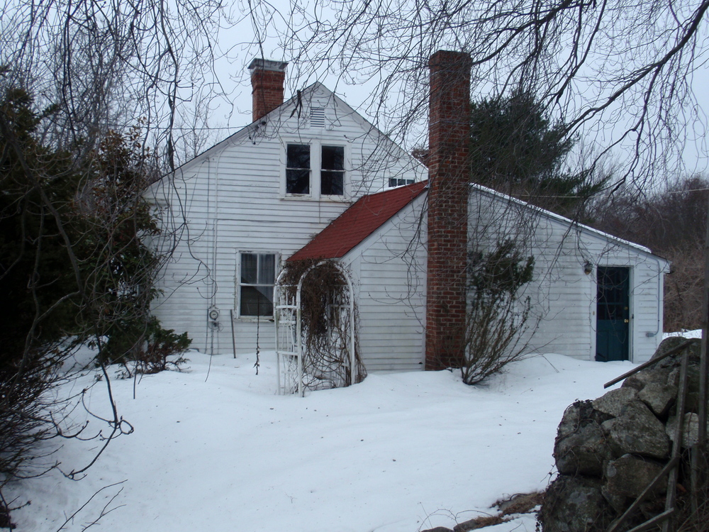  The east elevation, showing the ell that was added in the late 19th century to the side of the house. Much of the house is obscured by overgrown bushes. 