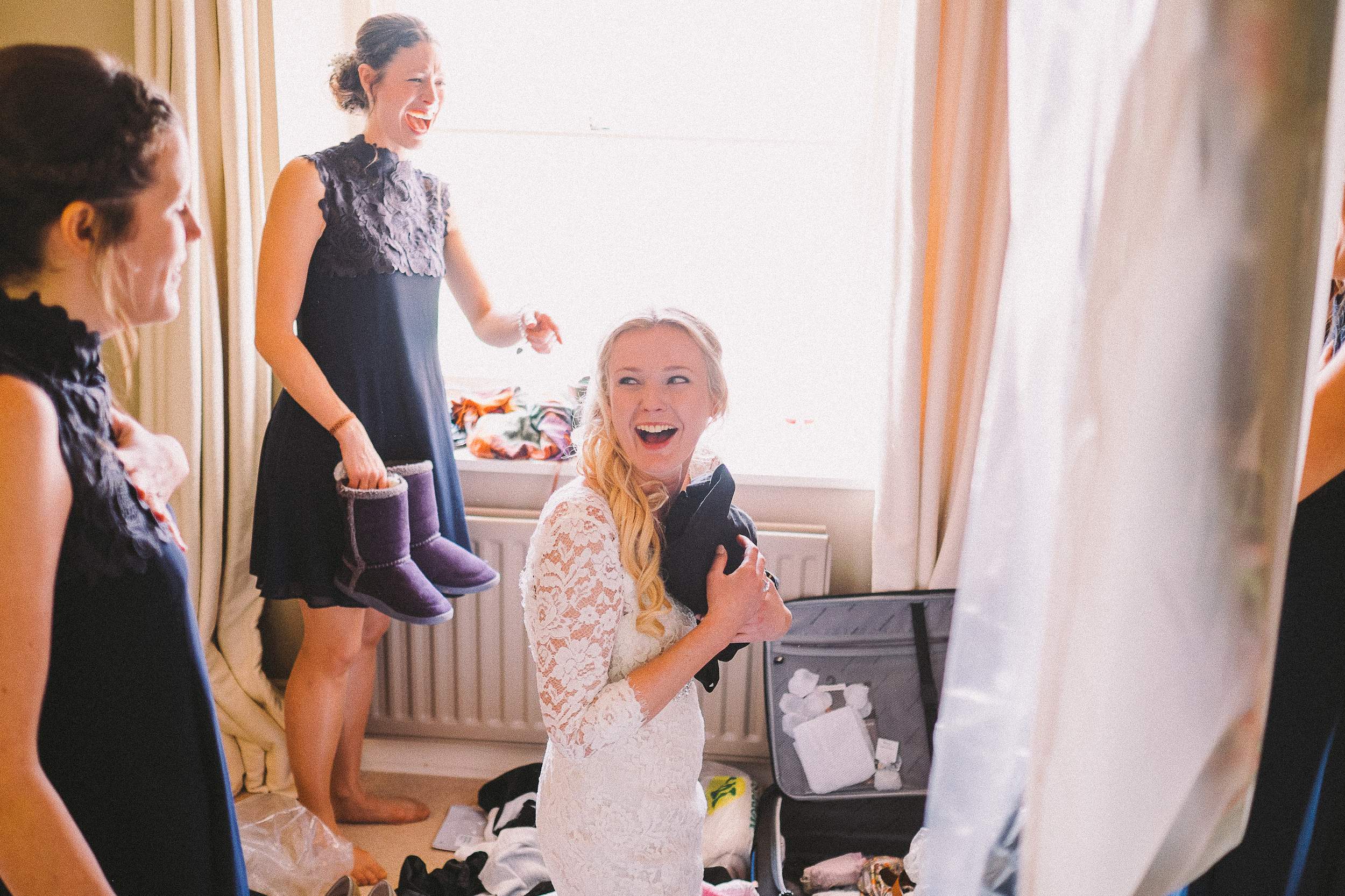 Bride clutching a bag, kneeling down among an open suitcase while one of her bridesmaids points and laughs. Why would this be in a wedding album?