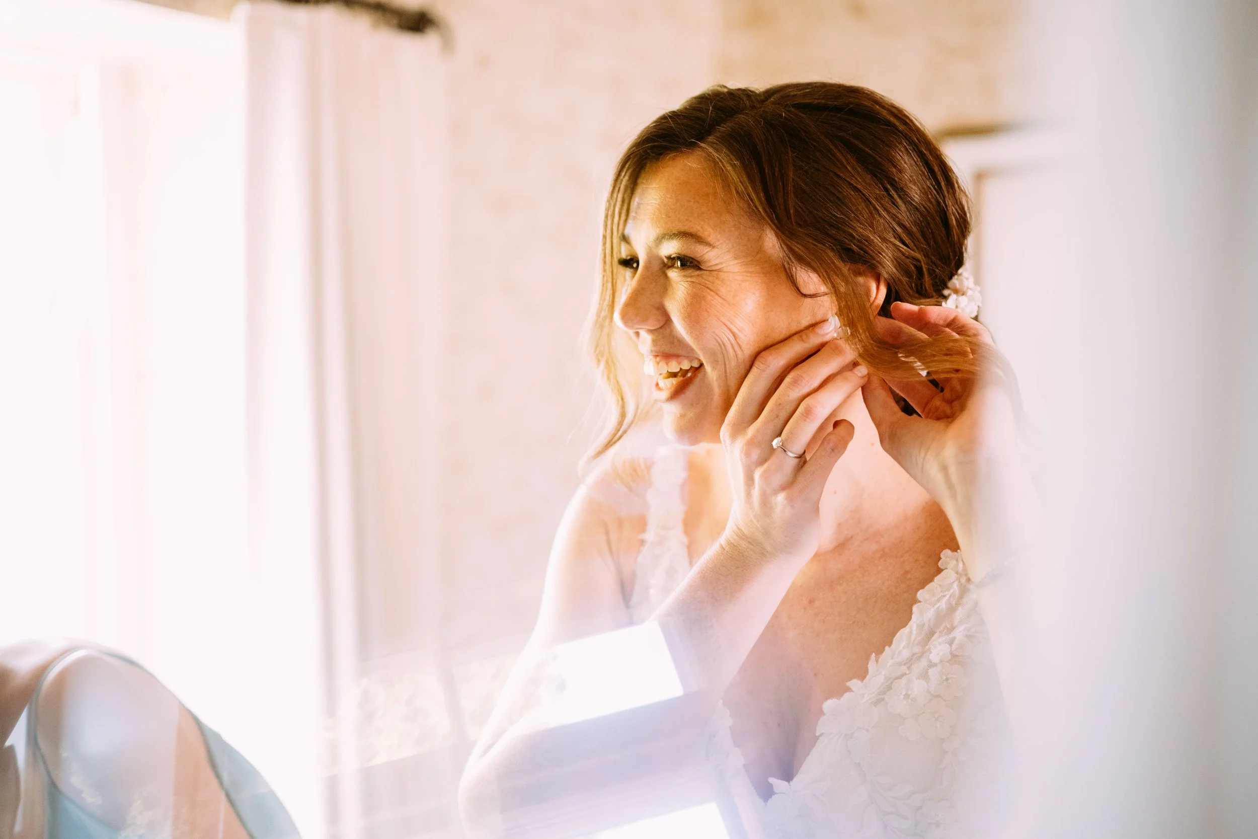 Happy bride putting on earrings