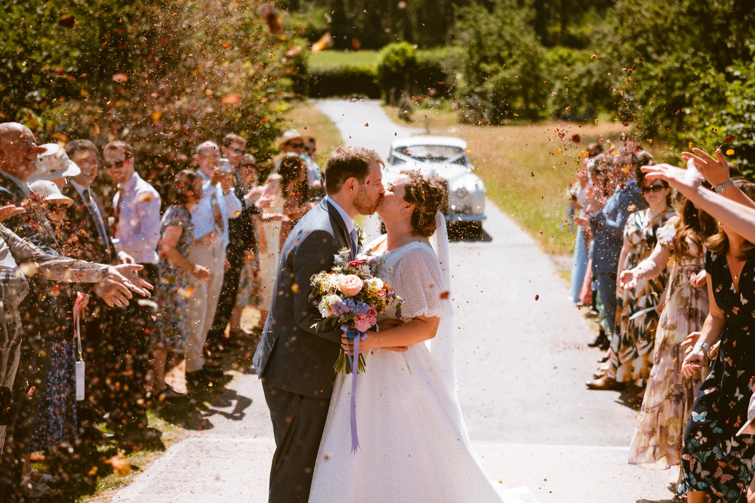 Bride and groom kissing during confetti