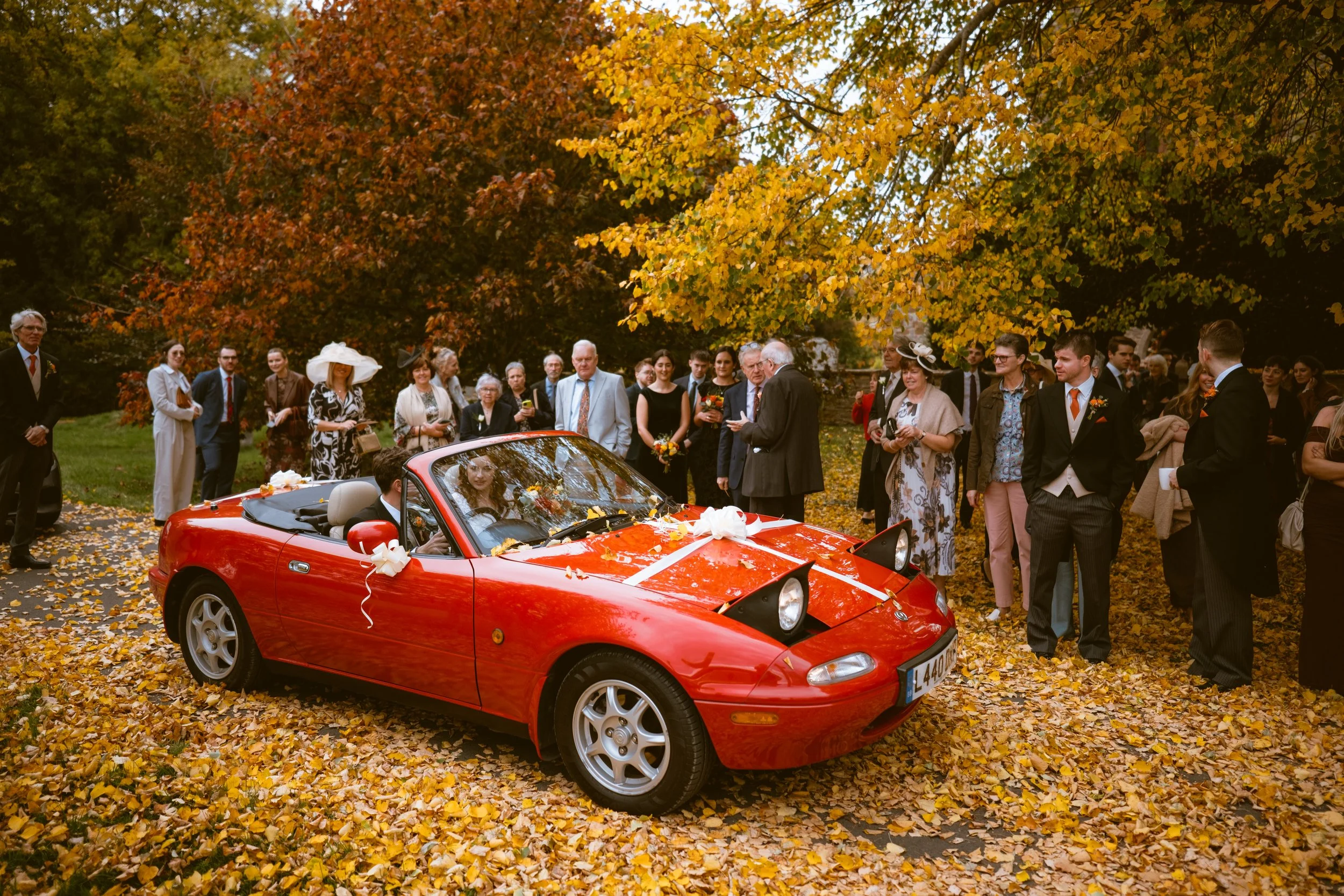 Bride and groom getting in a sports car for their wedding at Homme House