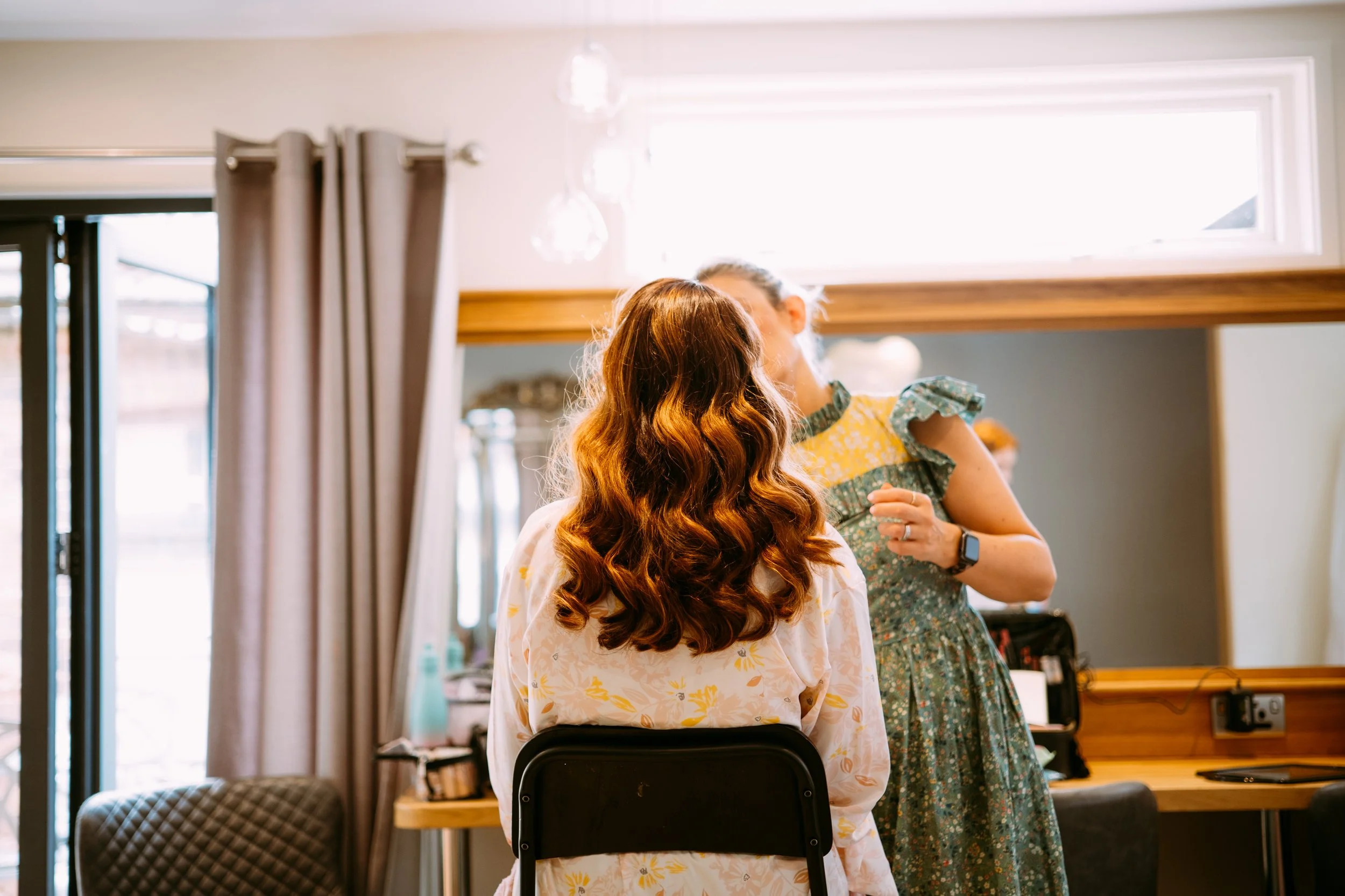 bride getting her hair done on the morning of a wedding