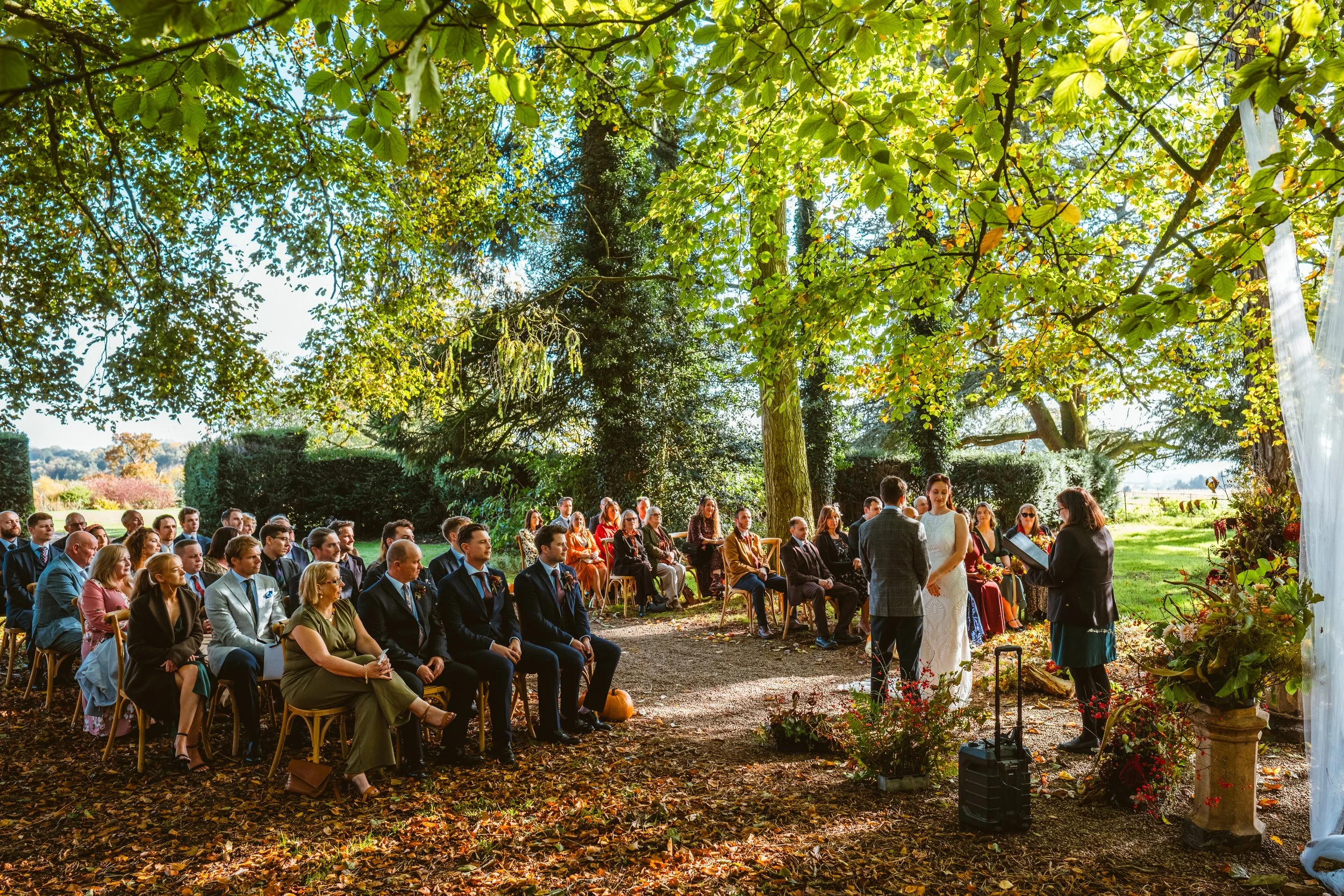 Outdoor autumn wedding ceremony beneath the trees in Herefordshire at Broadfield Court