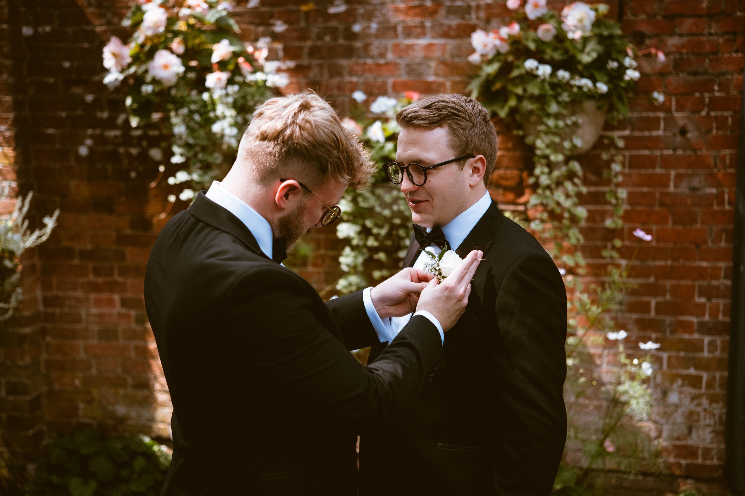 Groomsman helping with a buttonhole before the wedding ceremony at Davenport House