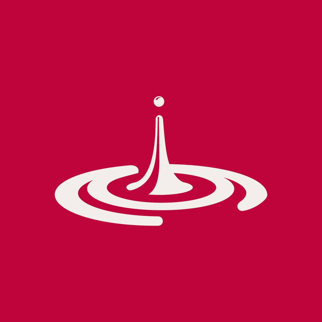 White droplet falling into red liquid, creating ripples.