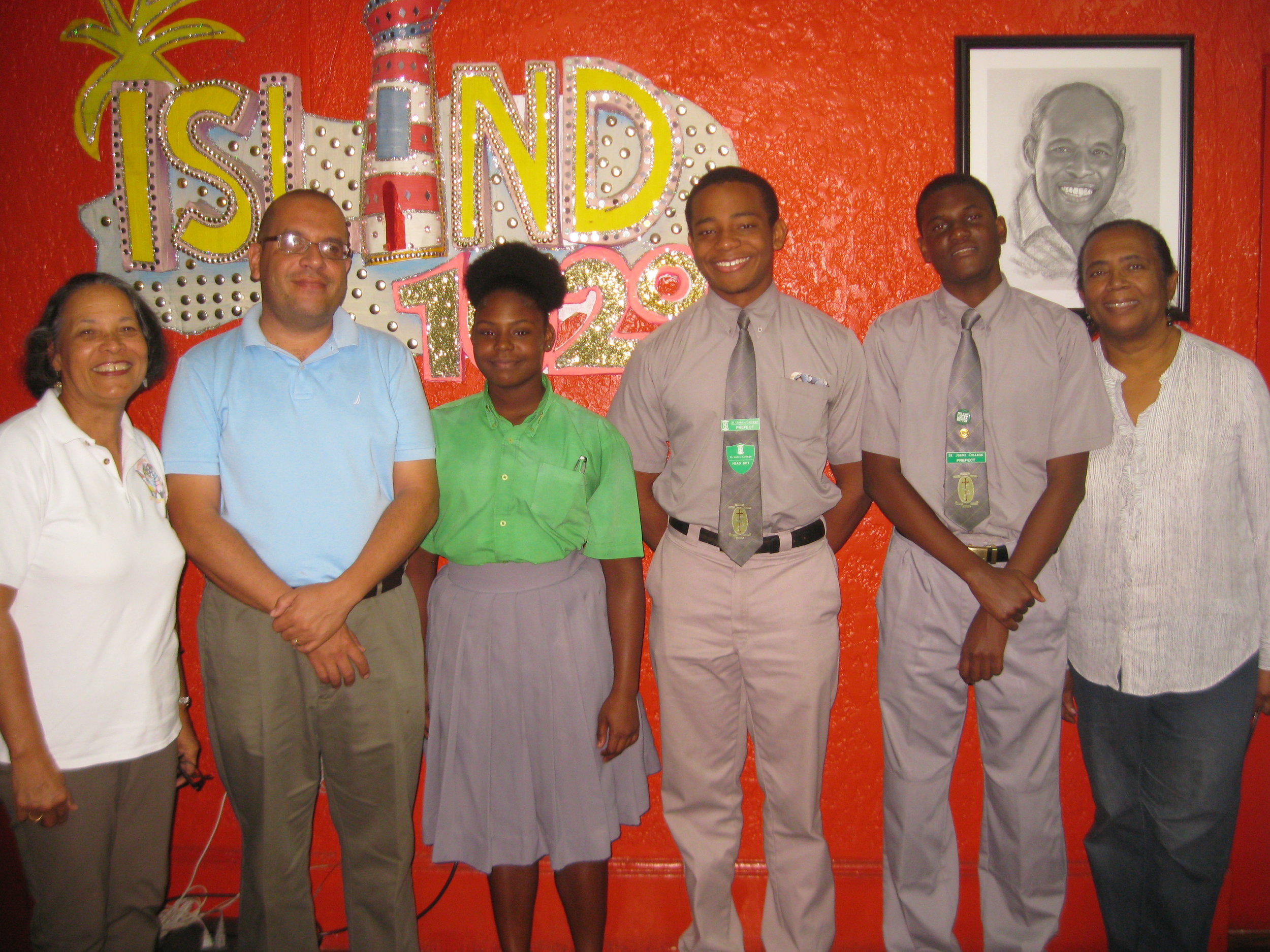 The radio studio photo shows (left to right): Pam, Father Turnquest, 11th Grade student Dwayna Archer, Head Boy and Team Leader Justyn Sweeting, 12th Grade student Richard Hanna and Patti.