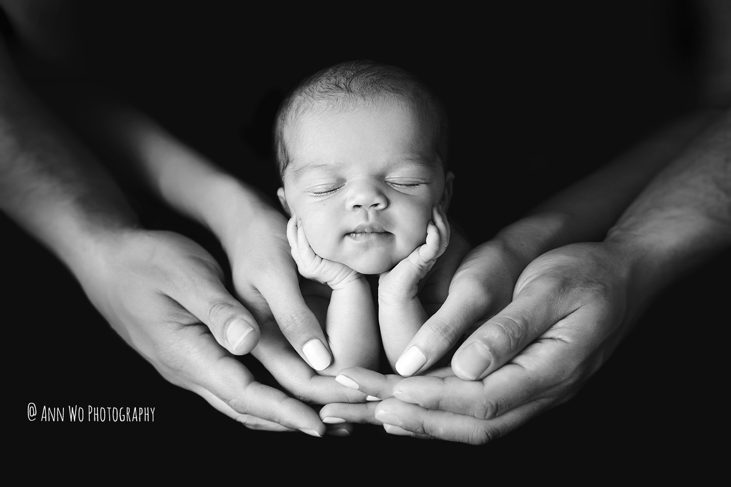 adorable newborn baby in parents' hands black and white