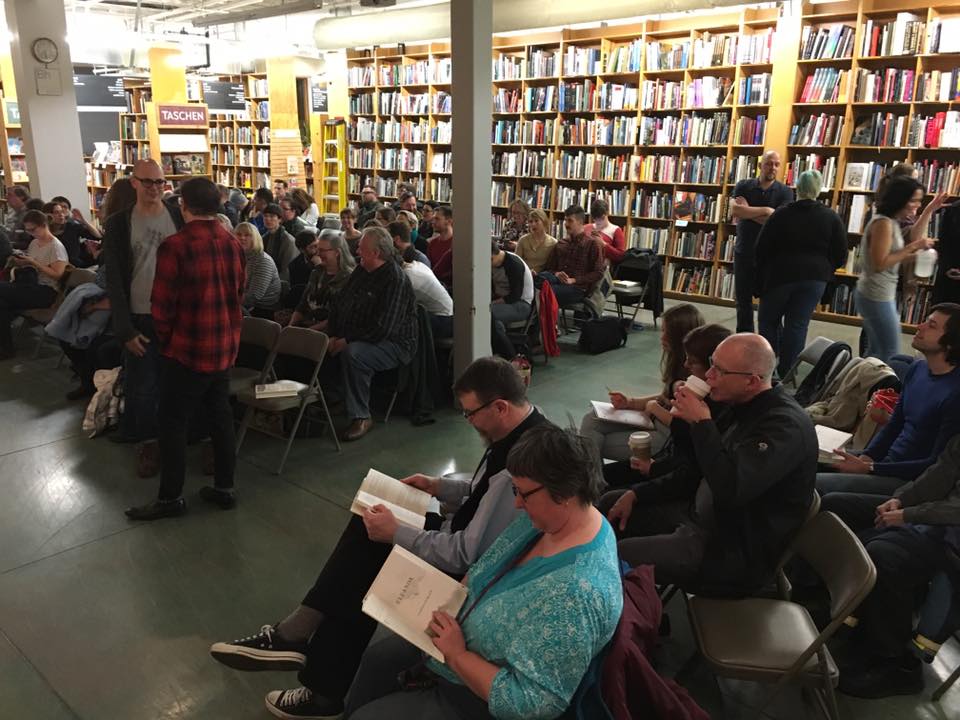 Nearly starting time! The room has mostly filled by now, including extra rows of chairs. So many familiar faces here—and, happily, quite a few unfamiliar ones as well.
