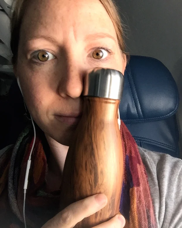 Taking a 5:00am flight with my go-to gear: S'well bottle , Apple headphones, scarf, jersey cardigan. 