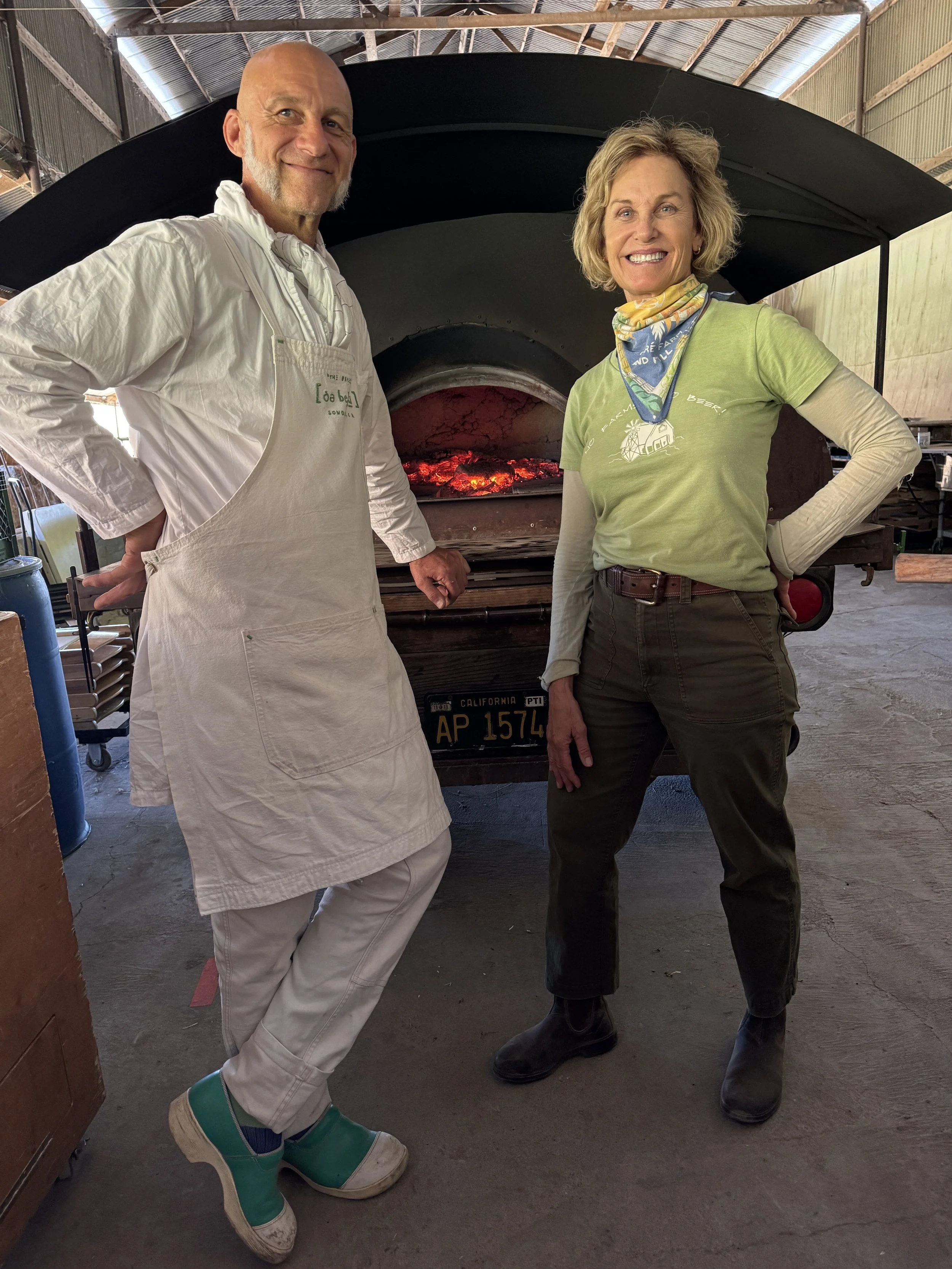 Mike Zakowski and Elizabeth beside the wood-fired oven before the harvest feast. Photo Credit: Elizabeth DeRuff