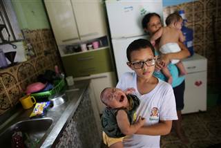 Paulo, 8, holds his five-month-old sister Laura as his grandmother Manyara (back), 46, holds her five-month-old grandson Lucas at their house in Santos, Sao Paulo state, Brazil on April 20, 2016. Jaqueline Jessica Silva de Oliveira hoped doctors were wrong when a routine ultrasound showed that one of her unborn twins would be born with the condition, marked by stunted head size and developmental issues. NACHO DOCE / Reuters