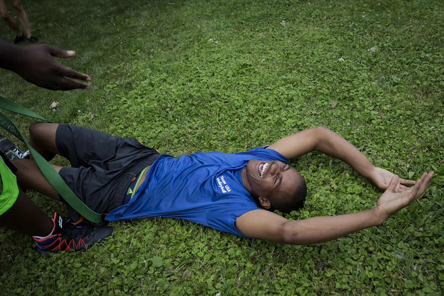 Grand Blanc, MI - Thursday, June 25, 2015: Athlete Dalvin Keller from Flint, MI laughs after collapsing on the ground during a resistance-band relay race on the lawn at Anytime Fitness in Grand Blanc, MI. The Michigan Special Olympics Volleyball Team has been preparing for the 2015 Special Olympics Summer Games in Los Angeles, CA beginning July 25. (Tim Galloway for ESPN)