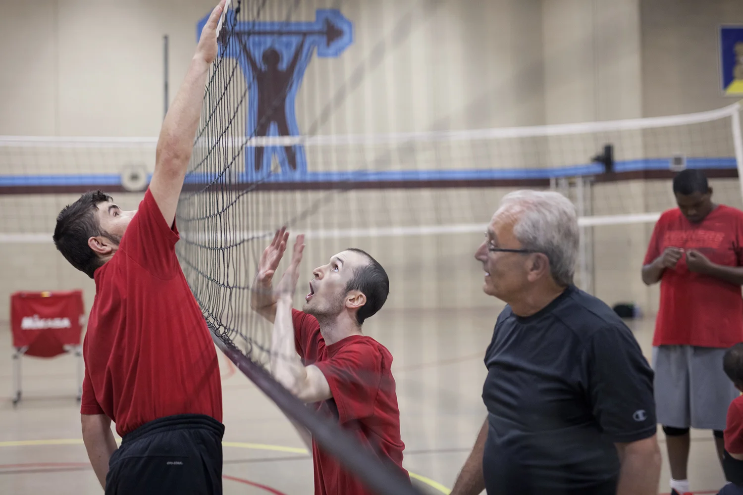 Flint, MI - Thursday, June 25, 2015: From left: Joe Gross from Montrose, MI pretends to spike a ball over the net as Brett Rife from Flint, MI attempts to block it while Coach Joe Finateri from Grand Blanc, MI watches during practice at the Elmer A. Knopf Learning Center in Flint, MI. The Michigan Special Olympics Volleyball Team has been preparing for the 2015 Special Olympics Summer Games in Los Angeles, CA beginning July 25. (Tim Galloway for ESPN)