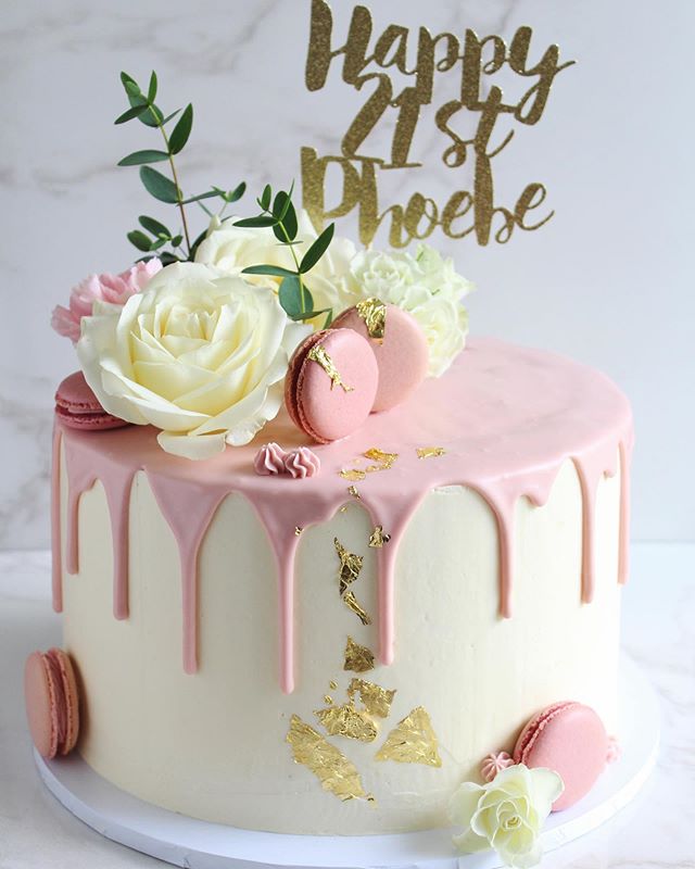 A white chocolate mud cake filled with maple caramel, finished with a white chocolate ganache drip, macarons, gold leaf and fresh flowers 🌷🌿 Can I turn 21 again, please?