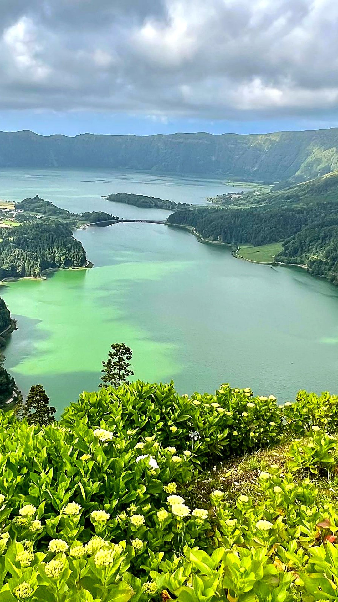 Fondo de pantalla móvil de un impresionante paisaje natural con un lago verde entre montañas en la isla de São Miguel, Azores, por Viajes Magazine.