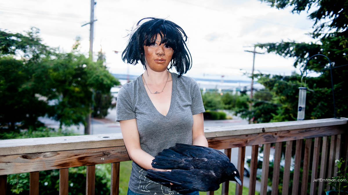  Kaeli Swift holds a stuffed crow while wearing a mask, replicating the pose used by her volunteers in a crow behavioral study.   