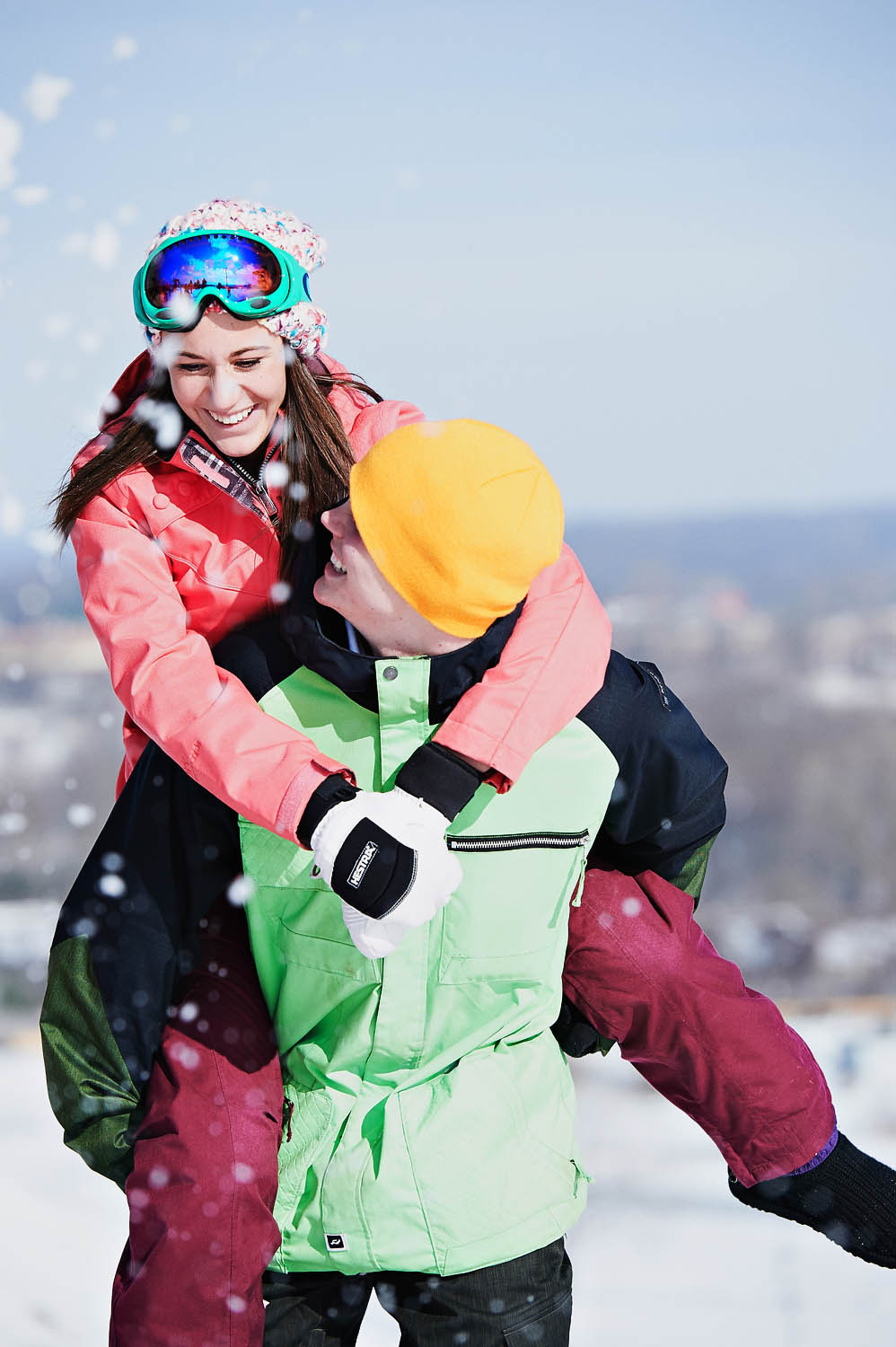 Couple in ski wear play around in the snow.