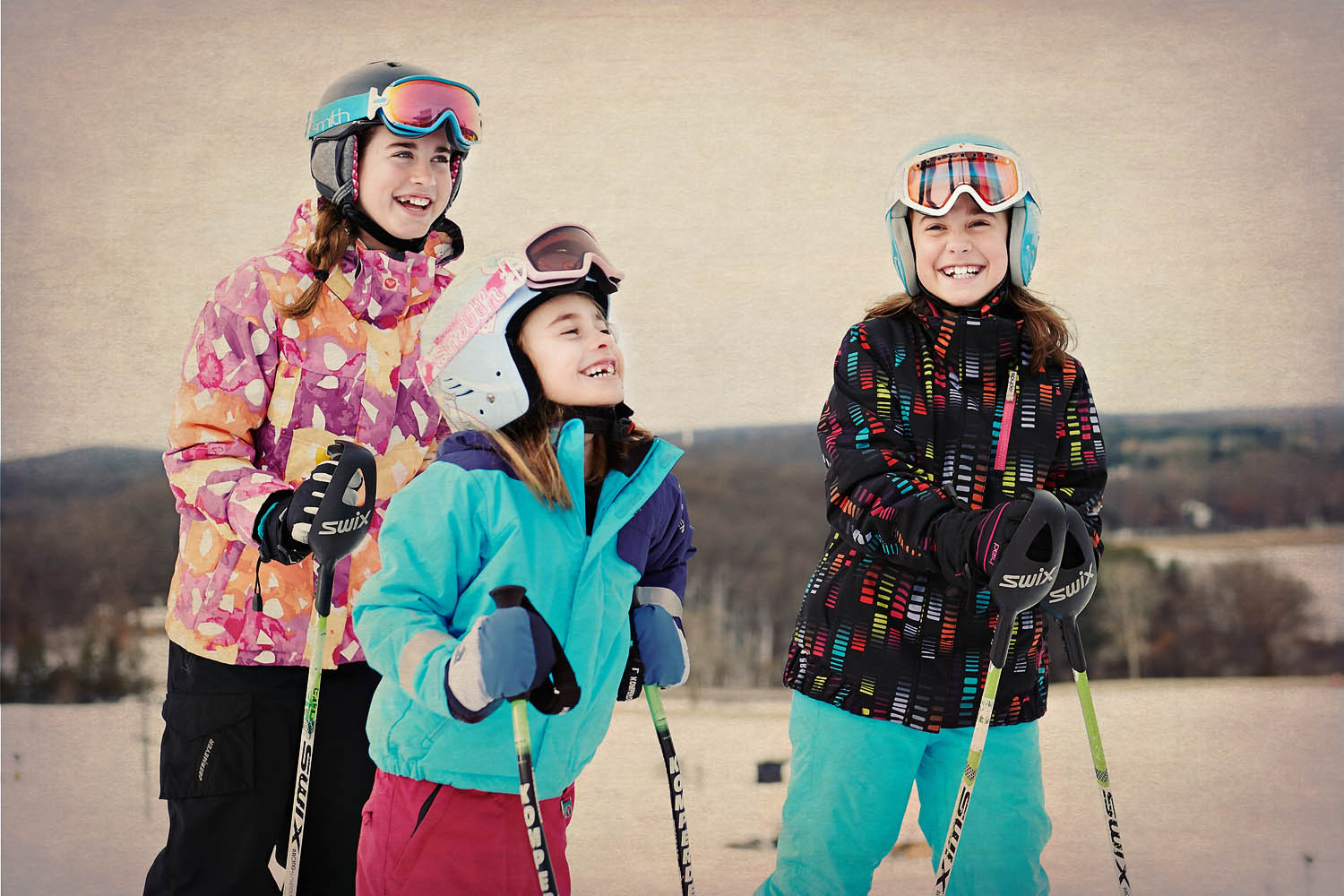 Group of kids laugh and enjoy skiing.