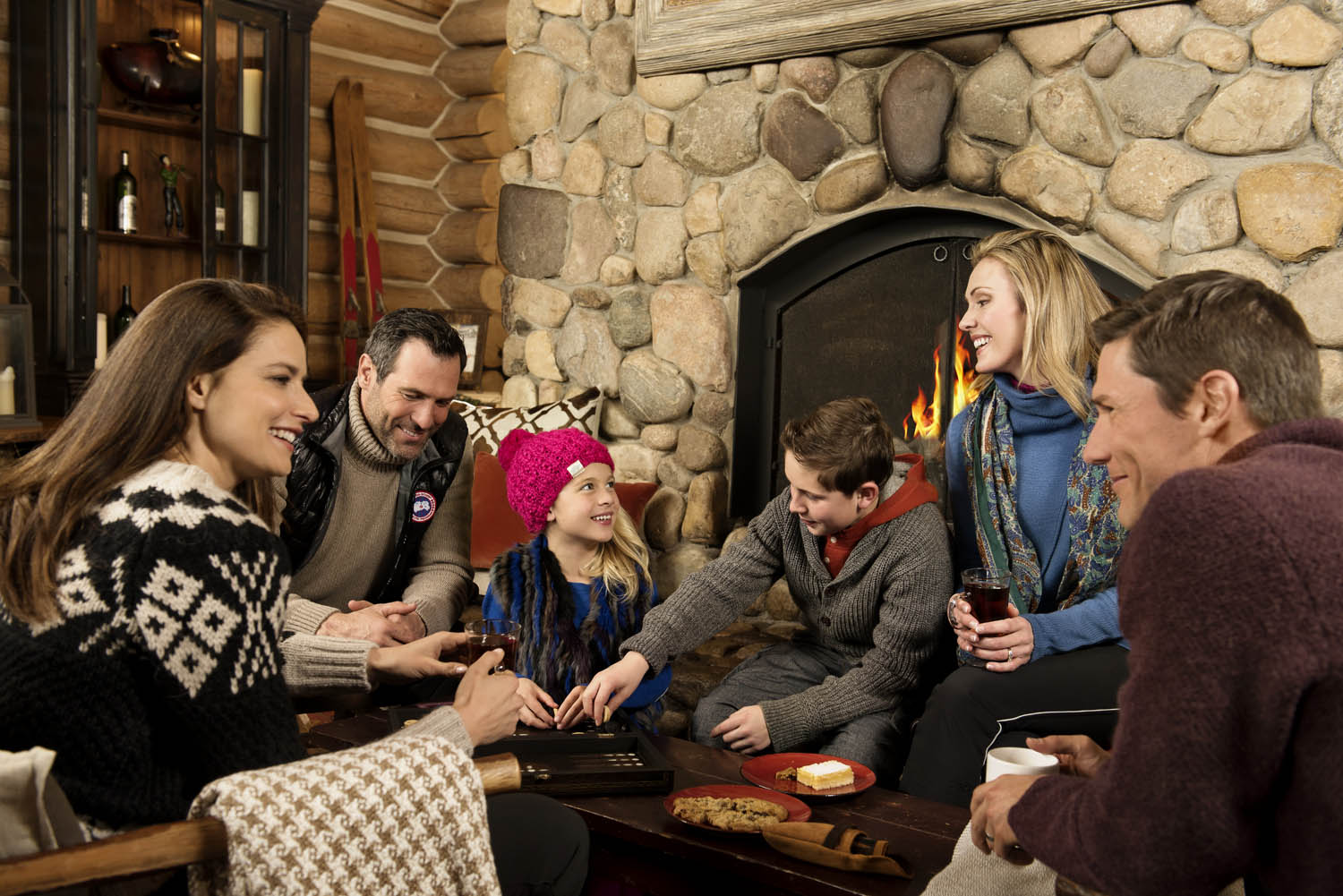 Family and group playing around fireplace at Beano's Cabin in Beaver Creek Colorado. Lifestyle advertising photography.