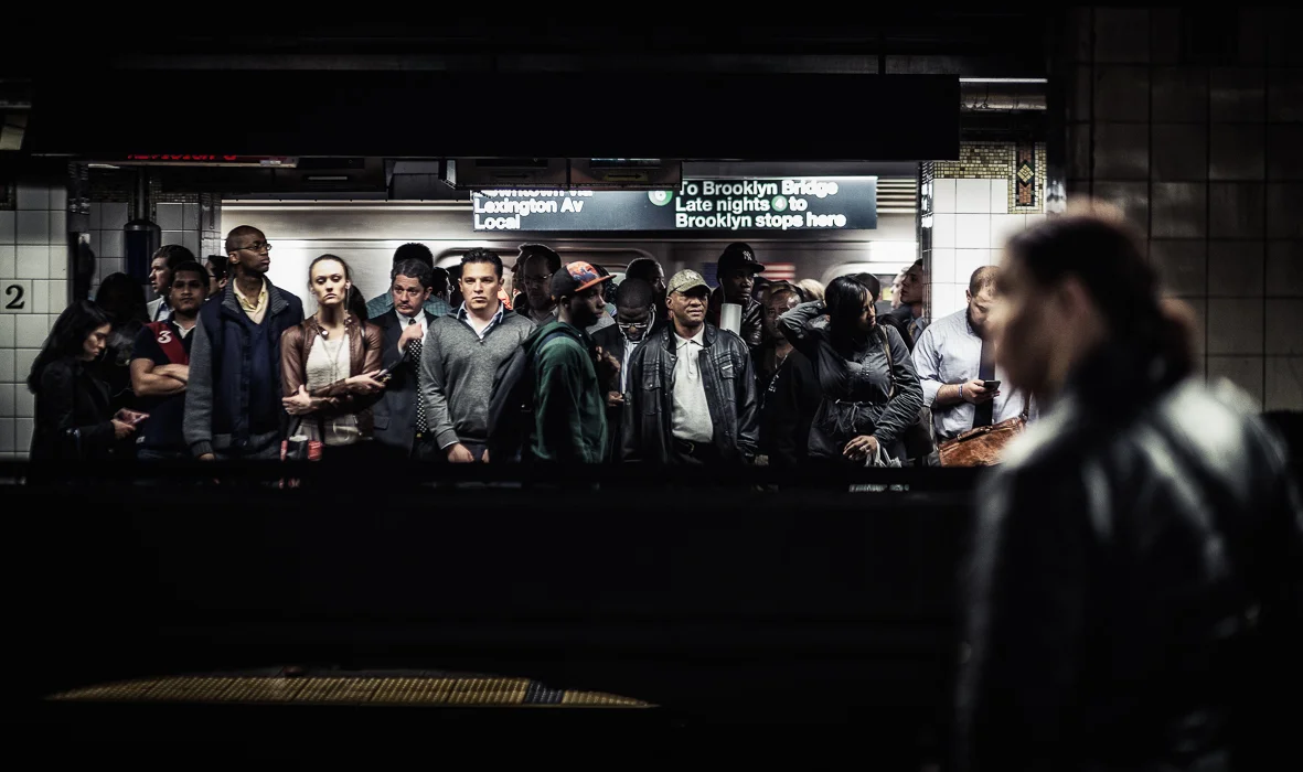 Crowded subway platform with diverse group of people waiting for a train in the subway station.