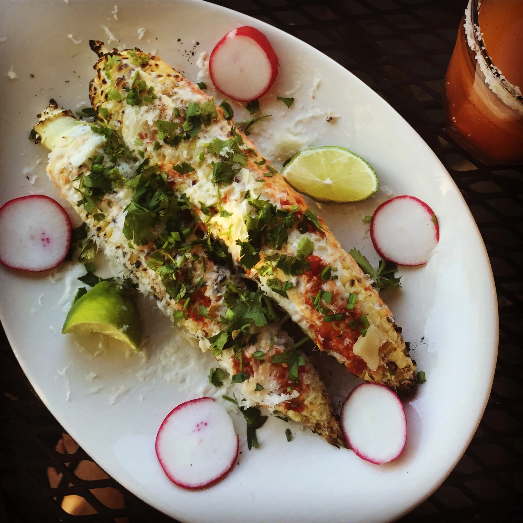 Mexican grilled corn elites with fresh cotilja cheese, spicy sauce, cilantro & lime