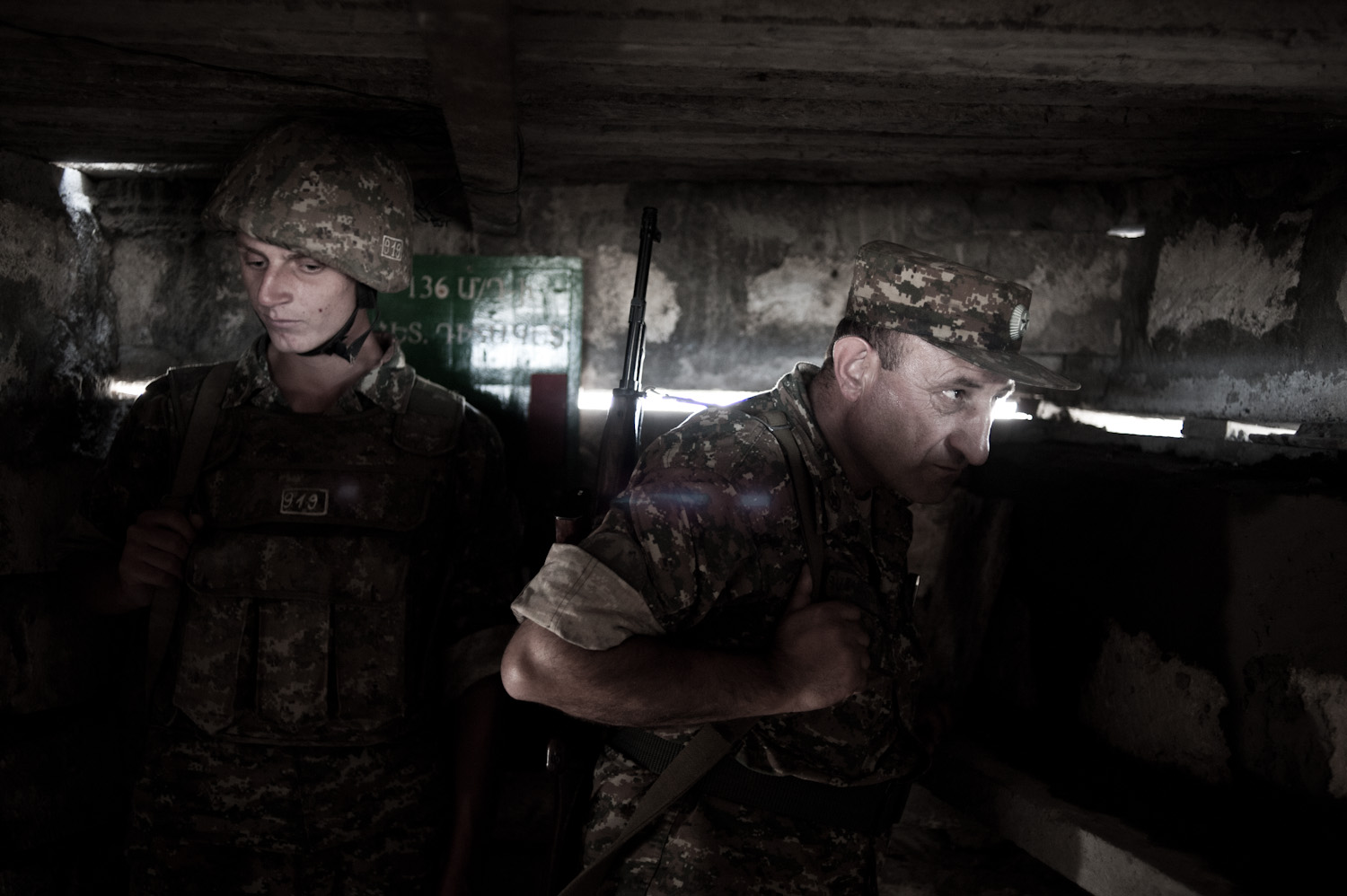  Colonel Alik Sargsyan watches the Azerbaijani frontline located 30 meters from his position at a lookout post, with young conscript Arman in the background.  