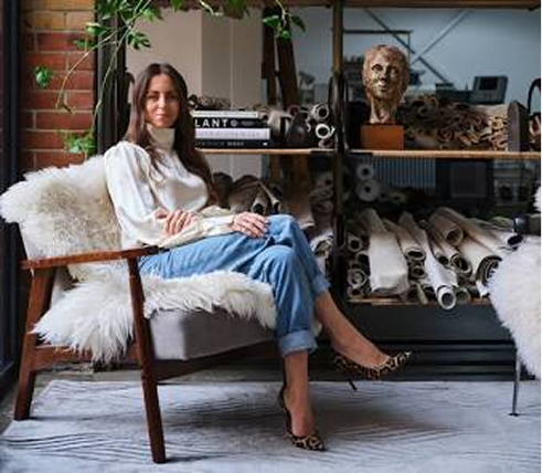 Image of the artist, Helen Amy Murray sitting on a chair in a modern and cozy room.
