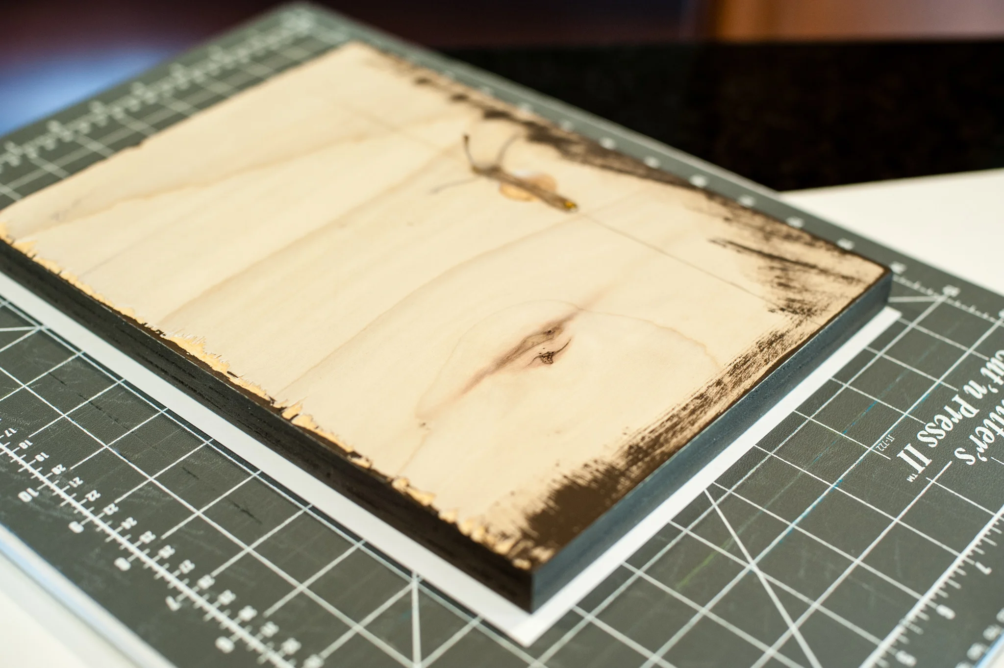 The image is now mounted on the board with the spray mount and flipped over. It's important to spray the wood and to spray the back of the image and then let sit for 60 seconds or so before you adhere them together - just follow directions on the back of the can. You can now see about 1/4 inch extra edge showing. I took an exact knife and trimmed along each side of the board. Note the center hole for hanging - the idea for this came directly from this YouTube video.