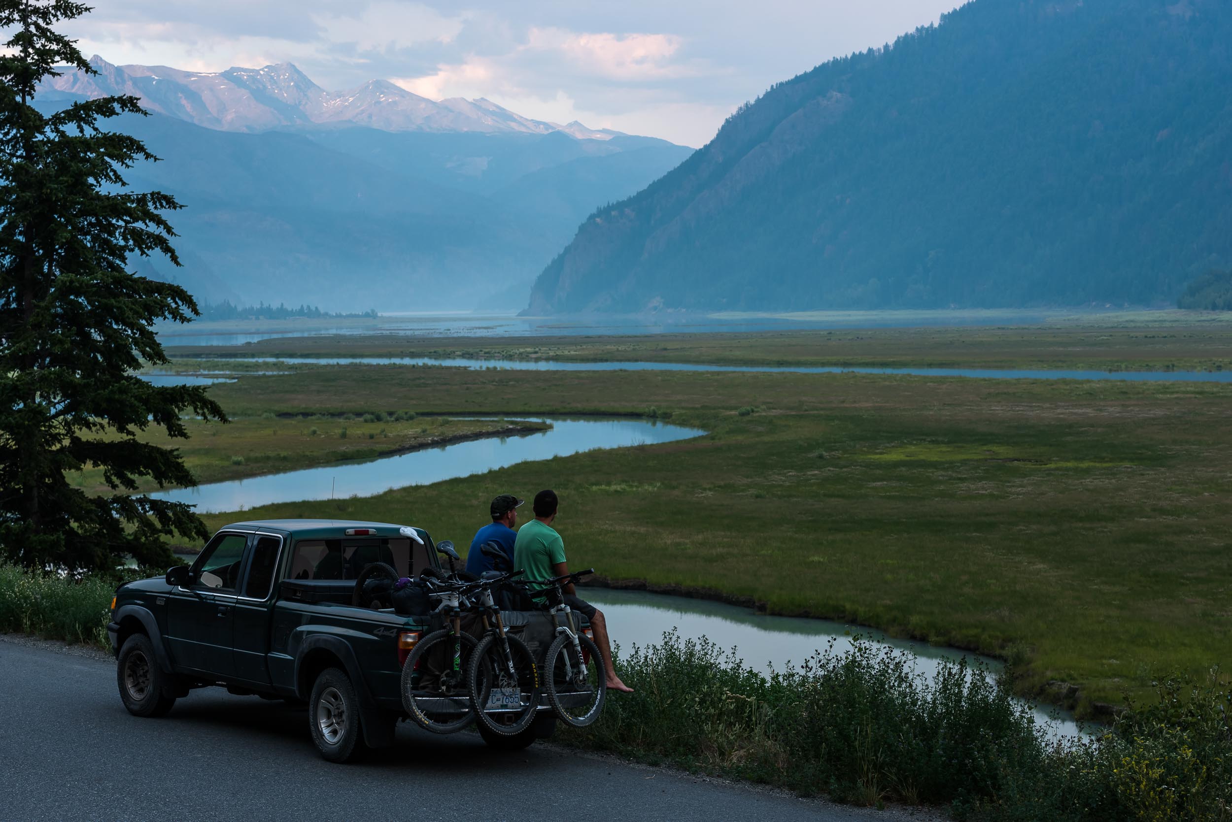 Mountain bikers sitting on a truck on the side of the road near Gold Bridge in the Bridge River Valley. Credit: BC/Reuben Krabbe