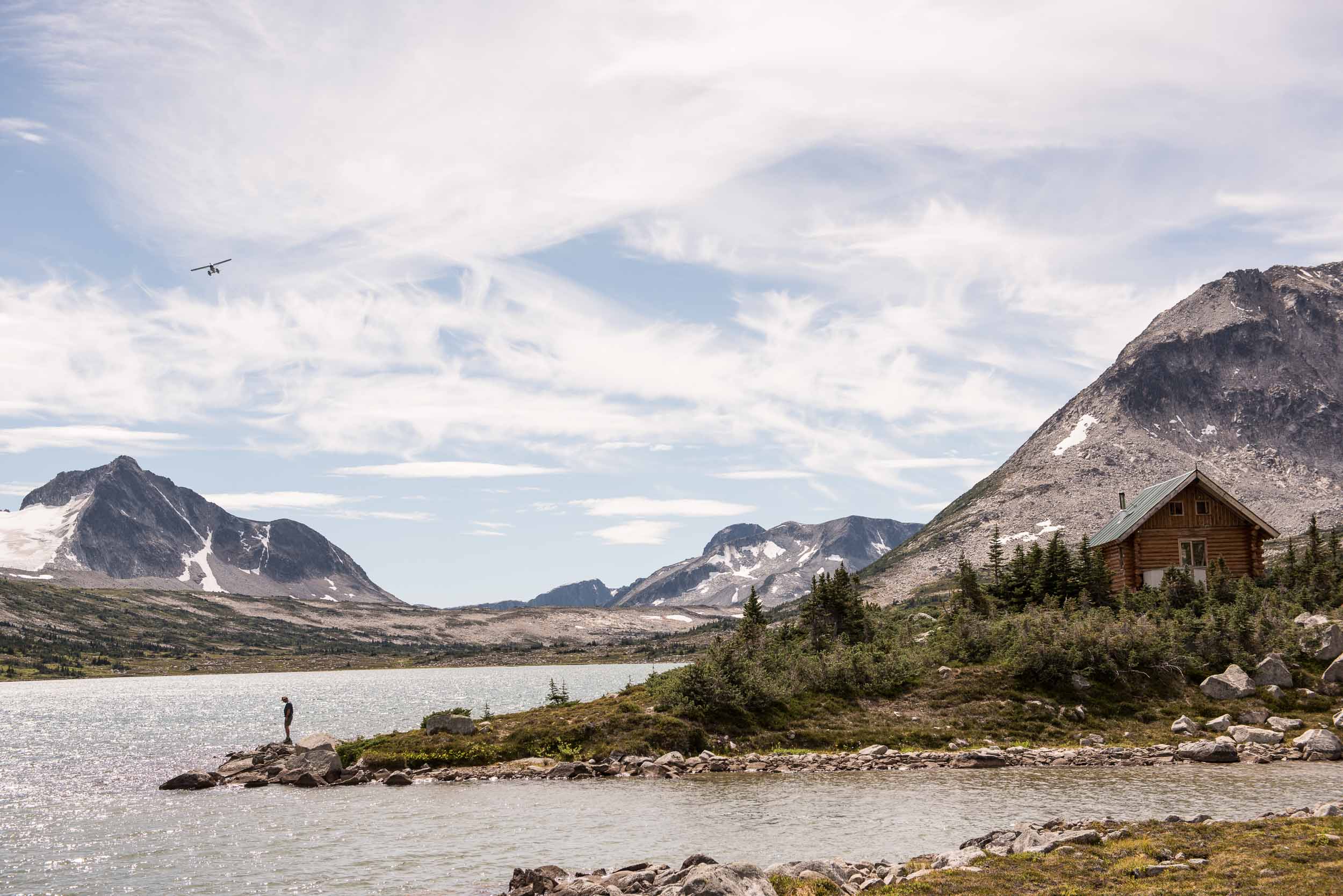 A hiker waiting for a airplane on the shores of Wilderness Lake. Credit: Destination BC/Kari Medig