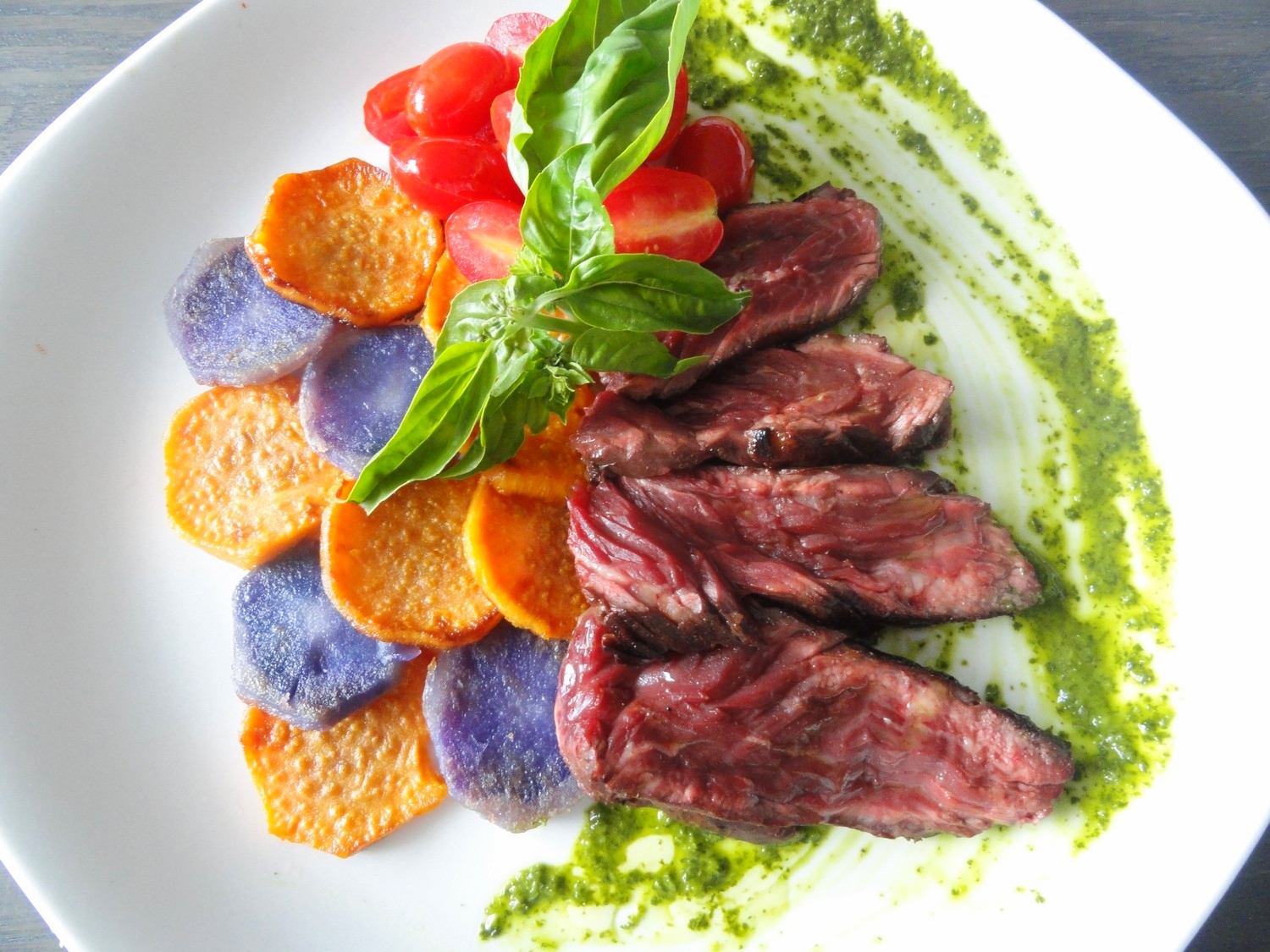 Seared beef controfiletto on chimichurri sauce with sweet and purple potato medallions