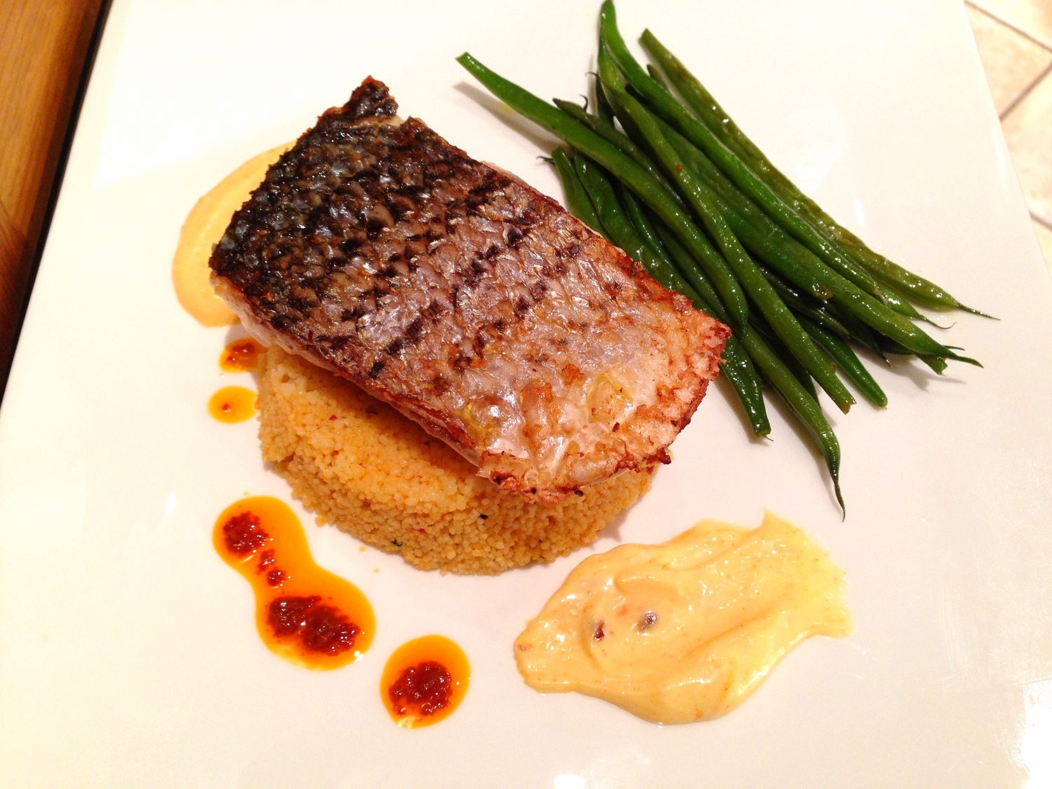 Striped bass on harissa couscous with haricots verts and saffron aioli