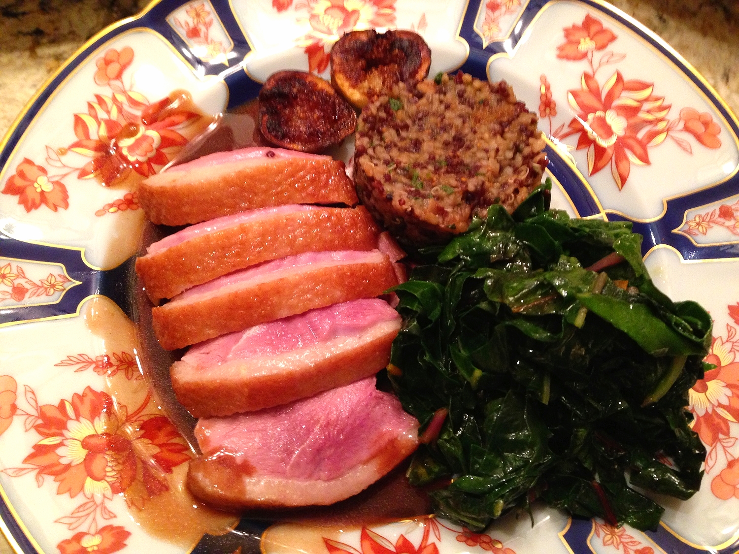 Seard duck breast with fig quinoa, garlic wilted greens, and caramelized figs in a sherry sauce