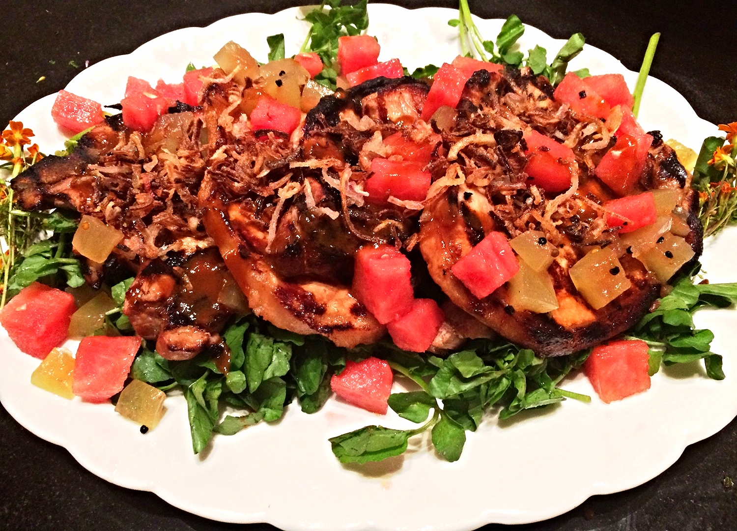 Vietnamese marinated porkchops on watercress with watermelon, pickled watermelon rind, crisped shallots and black sesame