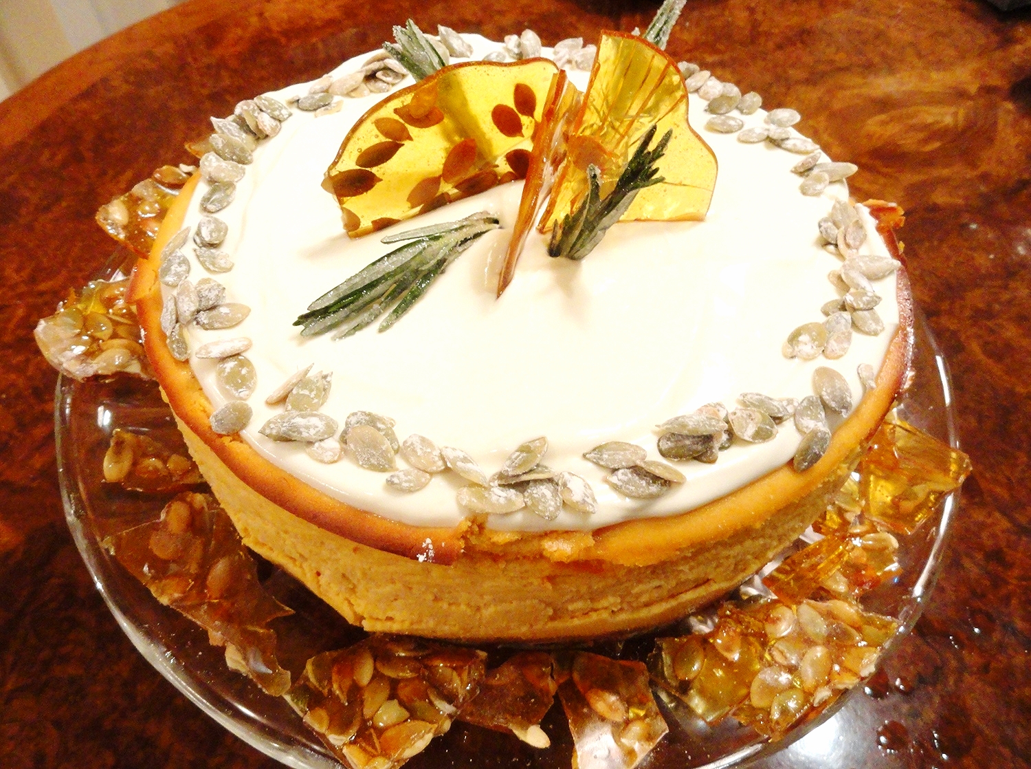 Pumpkin cheesecake, sweetened sour cream topping, sugared pepitas and rosemary, pumpkin seed brittle