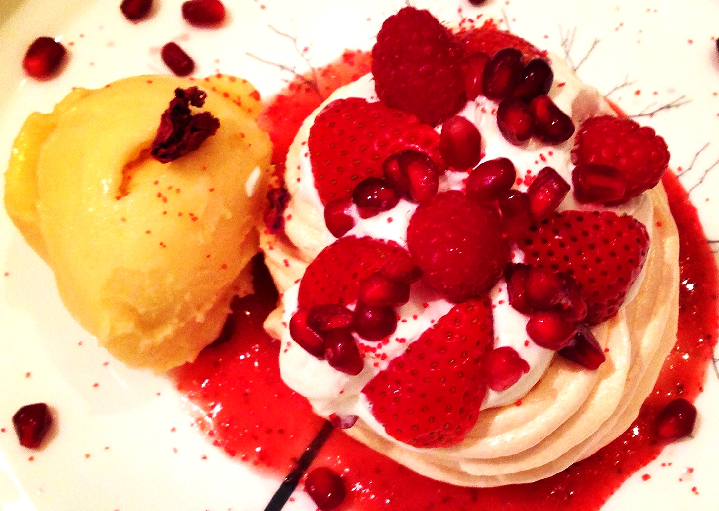 Mini Pavlova with creme chantilly, red fruits, strawberry sauce, and passion fruit sorbet