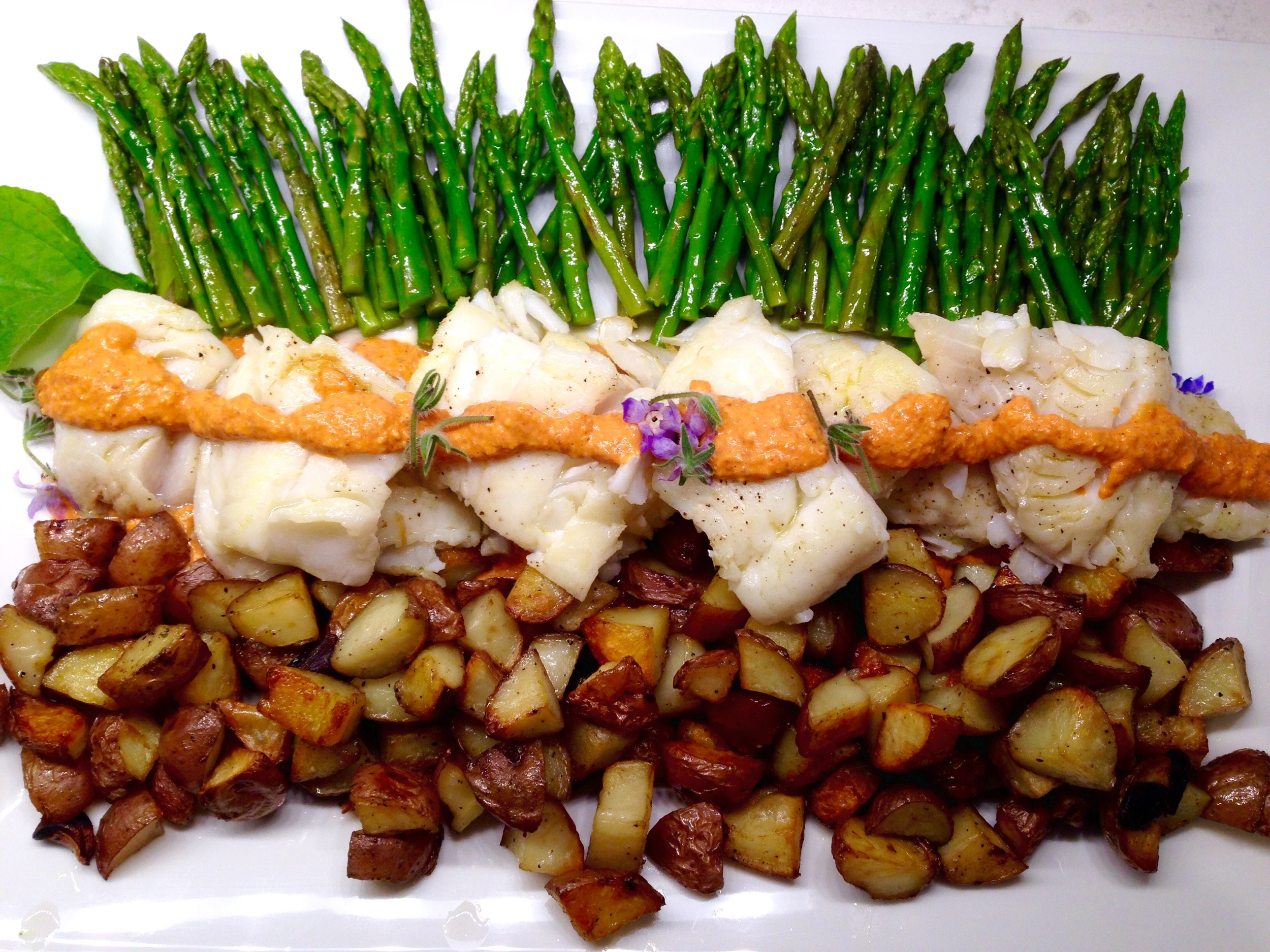 Cod fillets with romesco sauce, garlic-rosemary roasted potatoes, asparagus tips