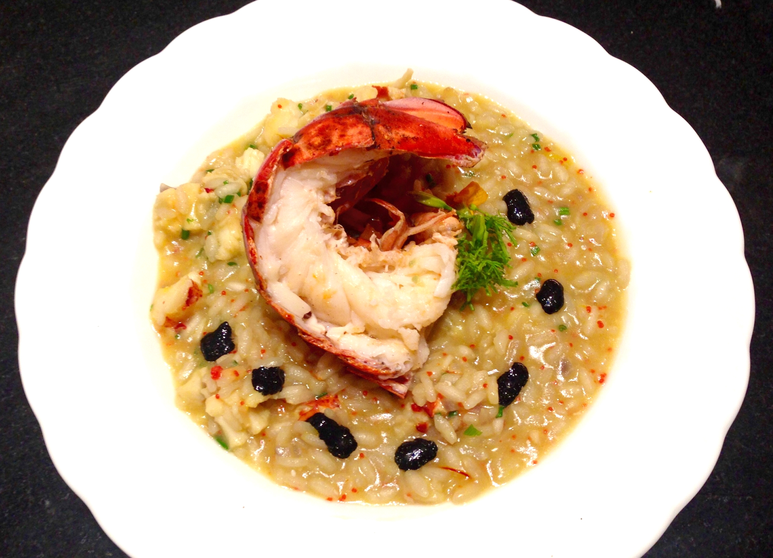 Lobster risotto with roasted lobster tail, lobster roe, chives, and squid ink sauce