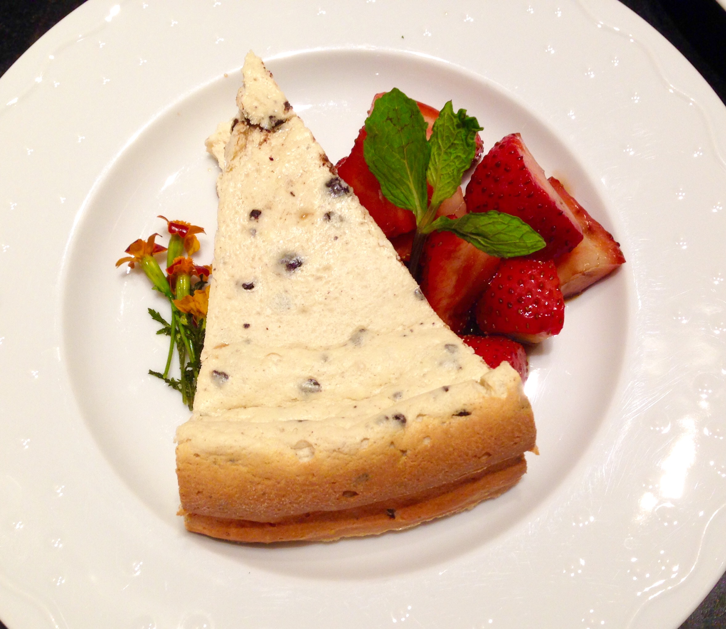 Ricotta-chocolate chip cheesecake, macerated strawberries, edible flowers