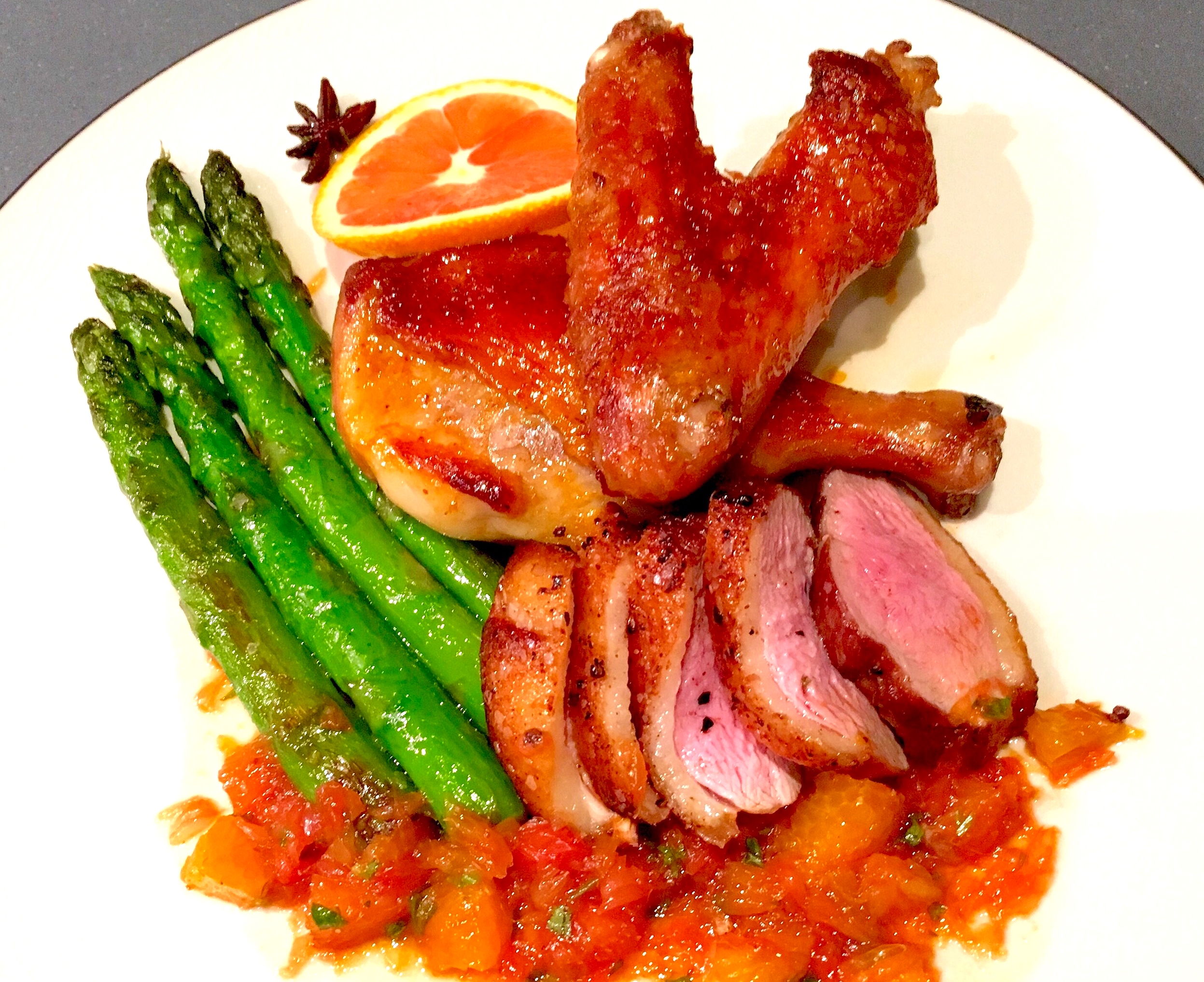 Roasted duck breast and leg with spiced citrus sauce and seared asparagus