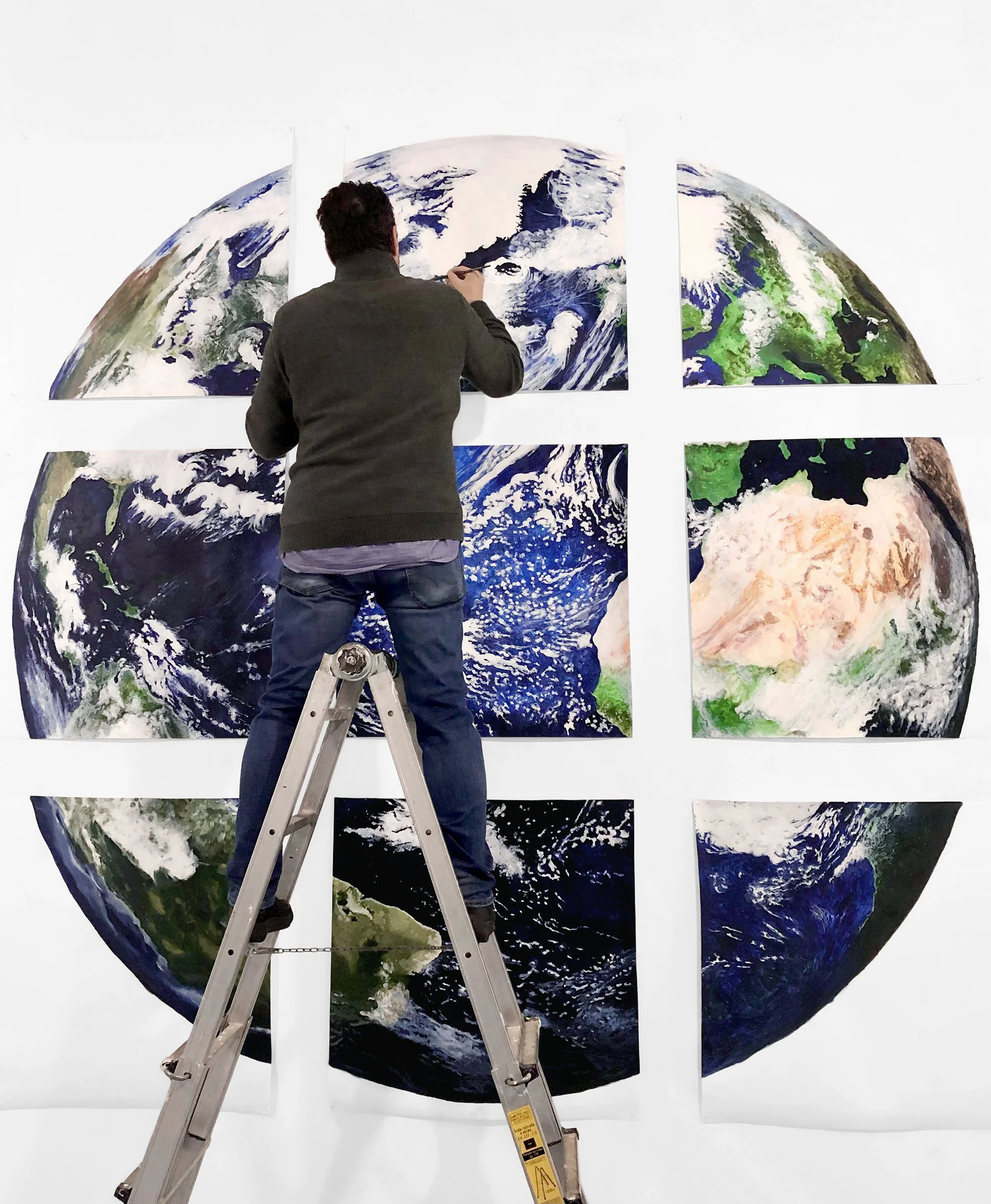 We Earth: the artist completing the work in art gallery