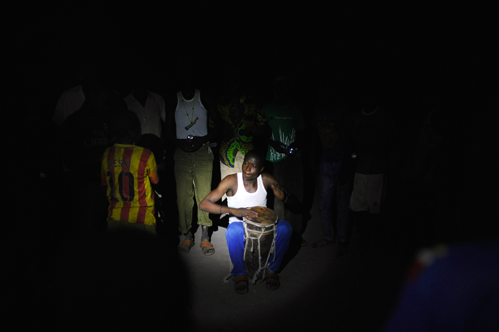 A boy plays a "tam-tam" at Mokolo Kambaya, Tandjilé, Chad in the middle of the night on 25 April 2015. Young catholics celebrate and dance near the catholic church without having electricity and without light. People got more and more scared of starting a fire or of dancing and singing because of Boko-Haram.