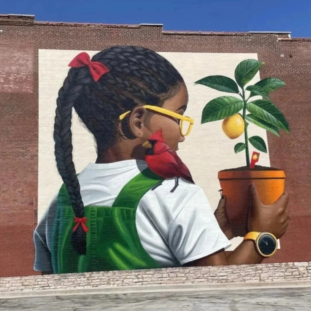 Dreams Do Come True mural by Joseph Mueller, depicting a young girl holding a potted lemon tree with a cardinal bird on her shoulder