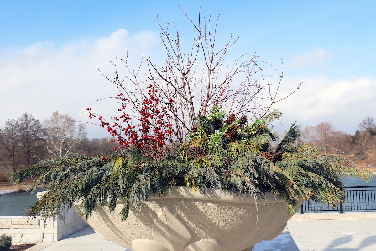 Photo of a large concrete planter overlooking Jefferson Lake filled with greenery, twigs, pinecones, berries and seed pods