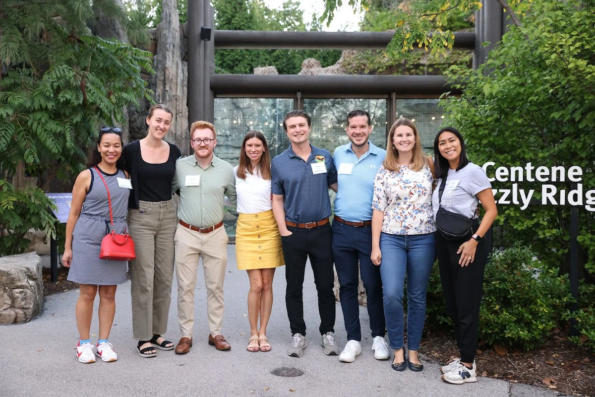 Members of the Forest Park Forever Young Friends board pose in front of Centene Grizzly Ridge at the Saint Louis Zoo