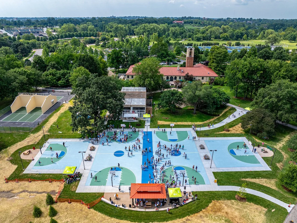 Aerial image of dozens of players and visitors enjoying the new bright blue and green basketball courts