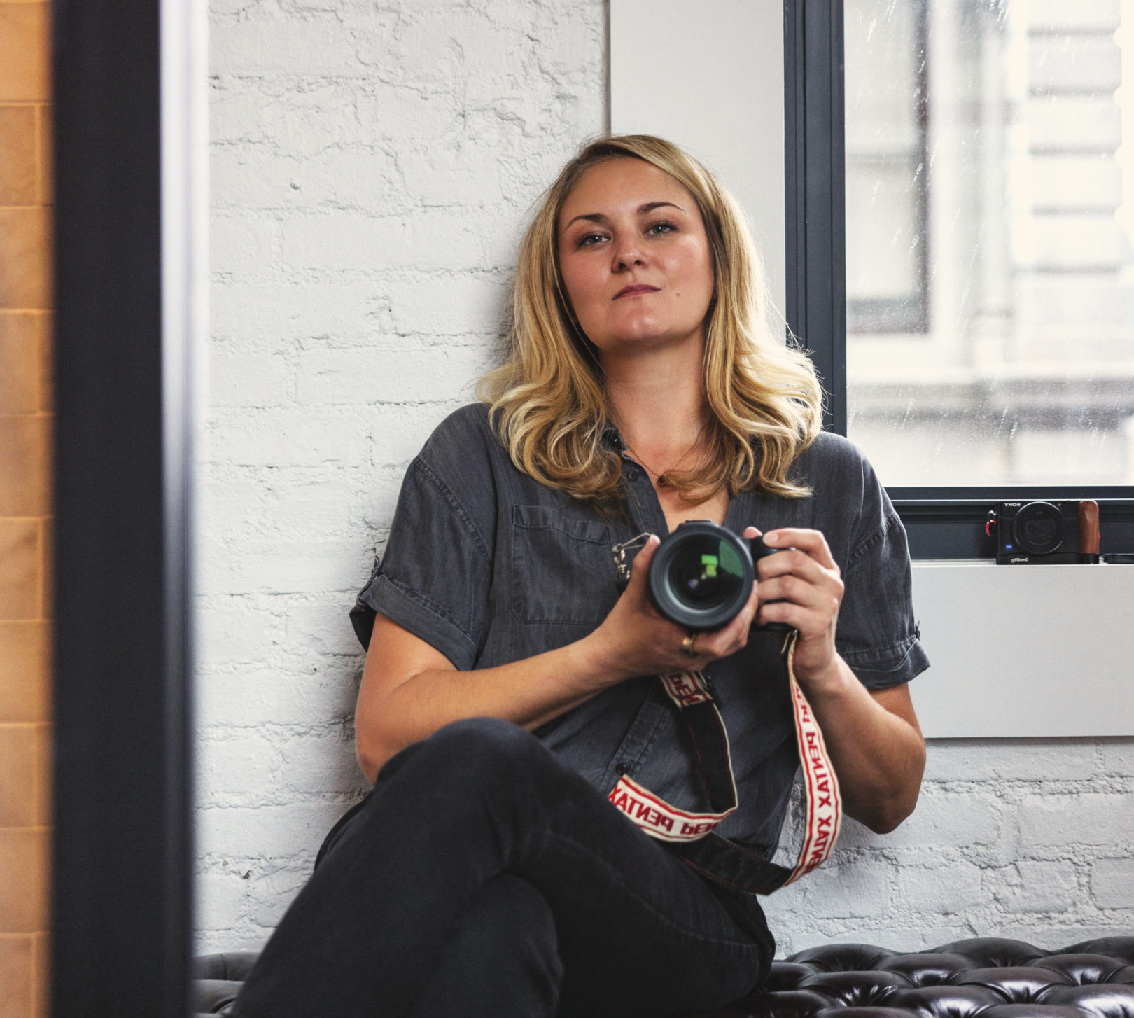 Katie Nixon sitting in a hotel room in New York City with Canon camera self-portrait