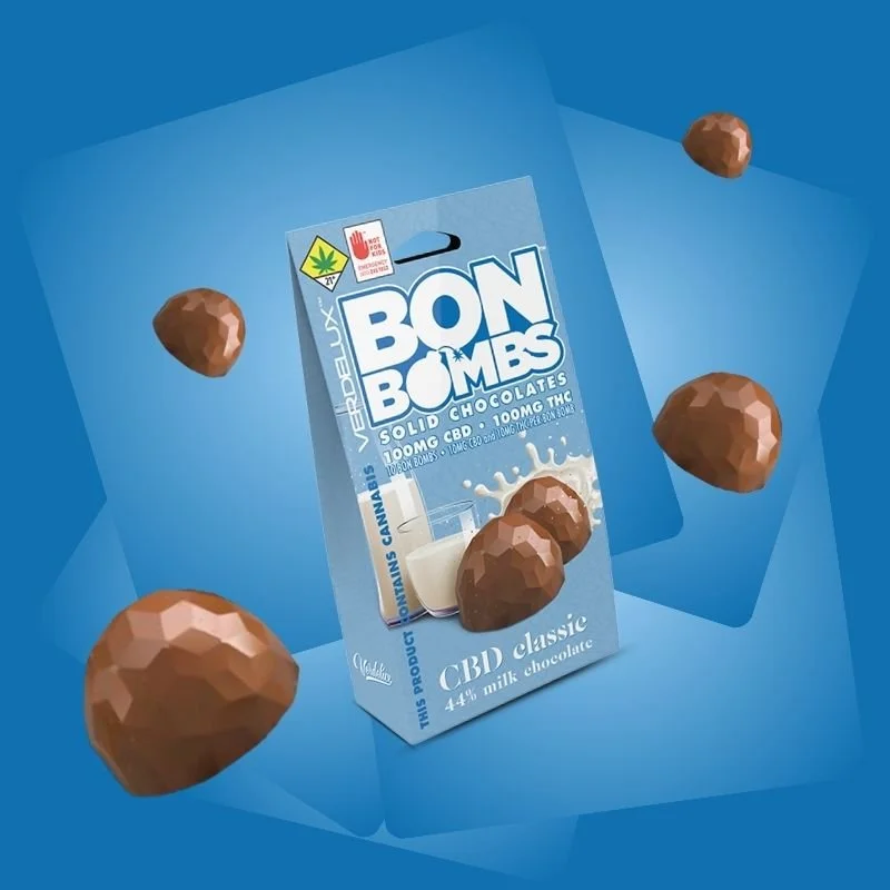 A package of Bon Bombs solid chocolates infused with CBD and THC, surrounded by floating, chocolate Bon Bombs against a blue background.