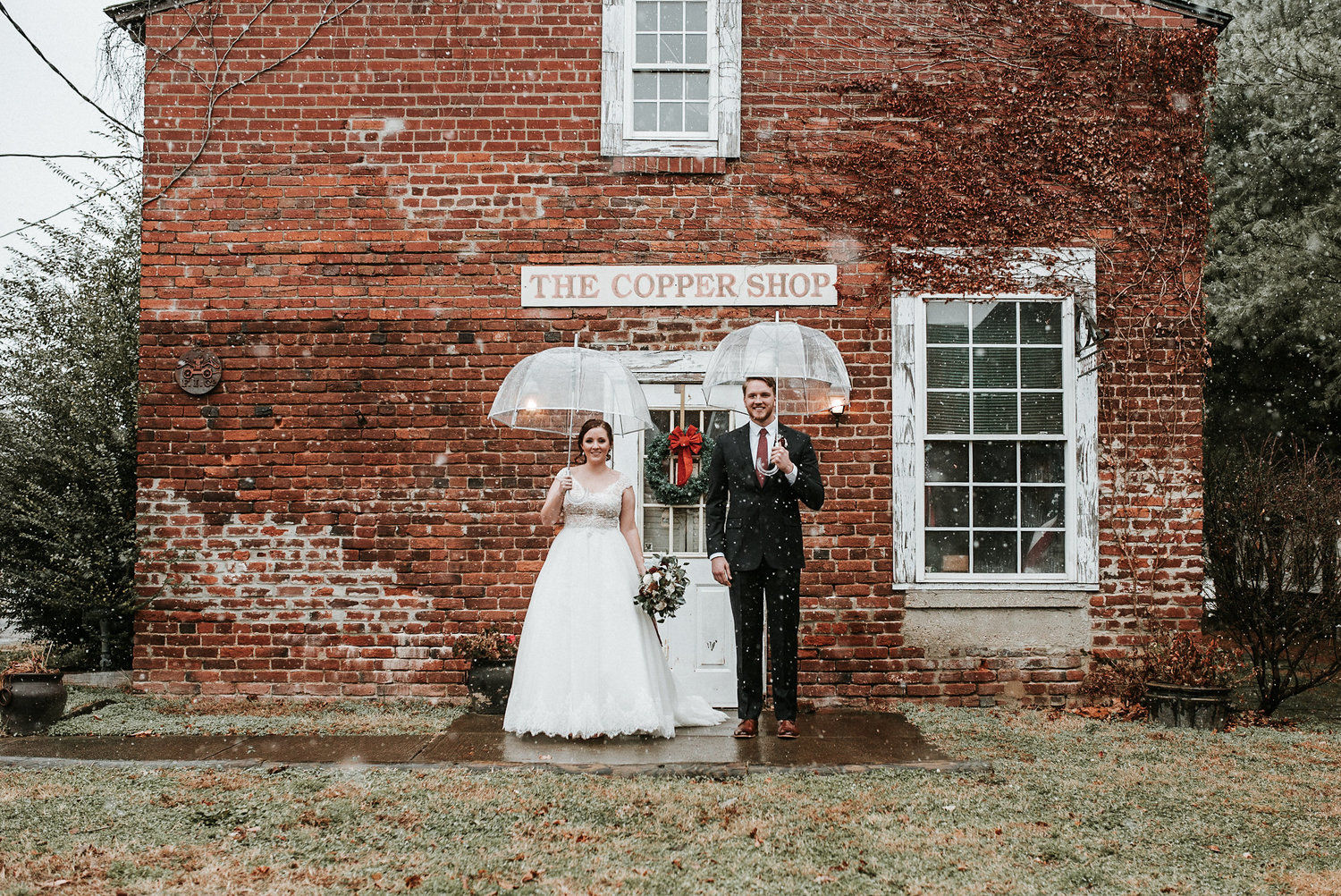 Bride+and+groom+standing+under+umbrellas.jpeg