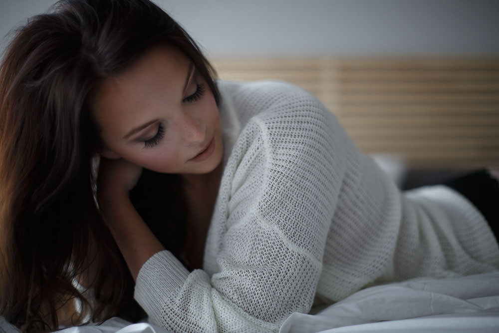 woman in sweater peeks over her shoulder at who could be her husband